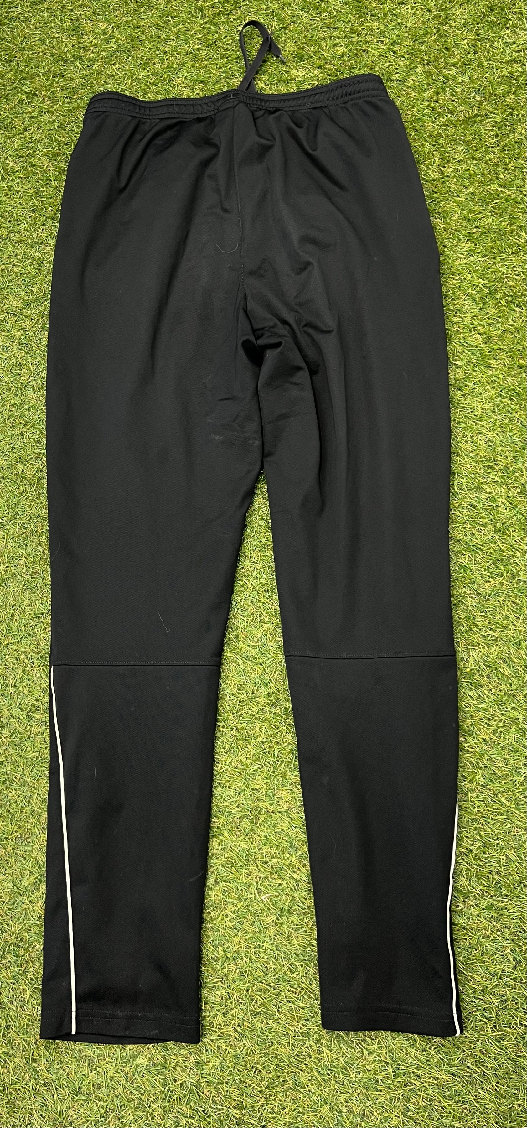 Back view of black Nike Dri-FIT tracksuit bottoms showing white piping detail on lower legs