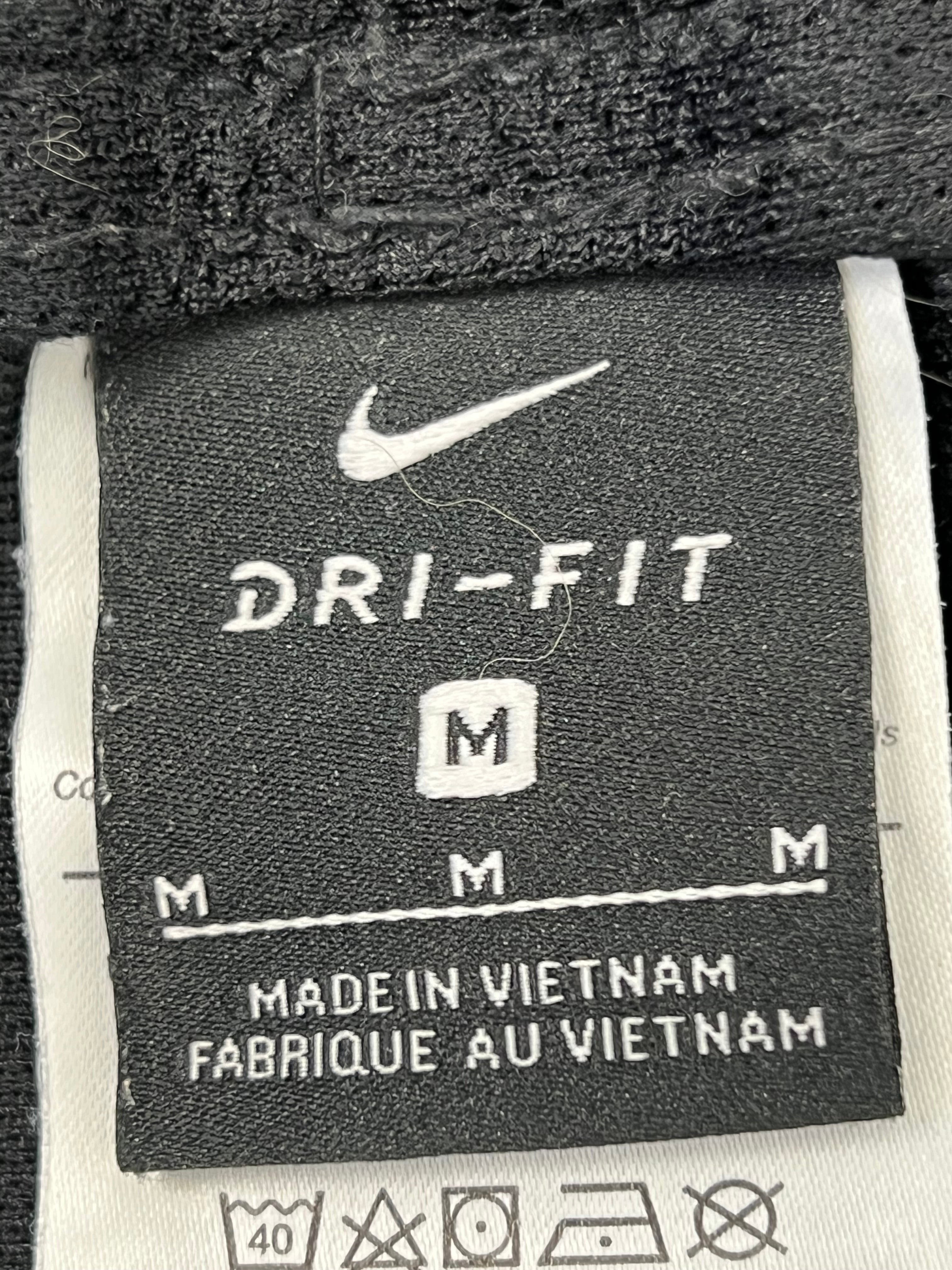 Close-up of black Nike Dri-FIT size label indicating medium and care instructions