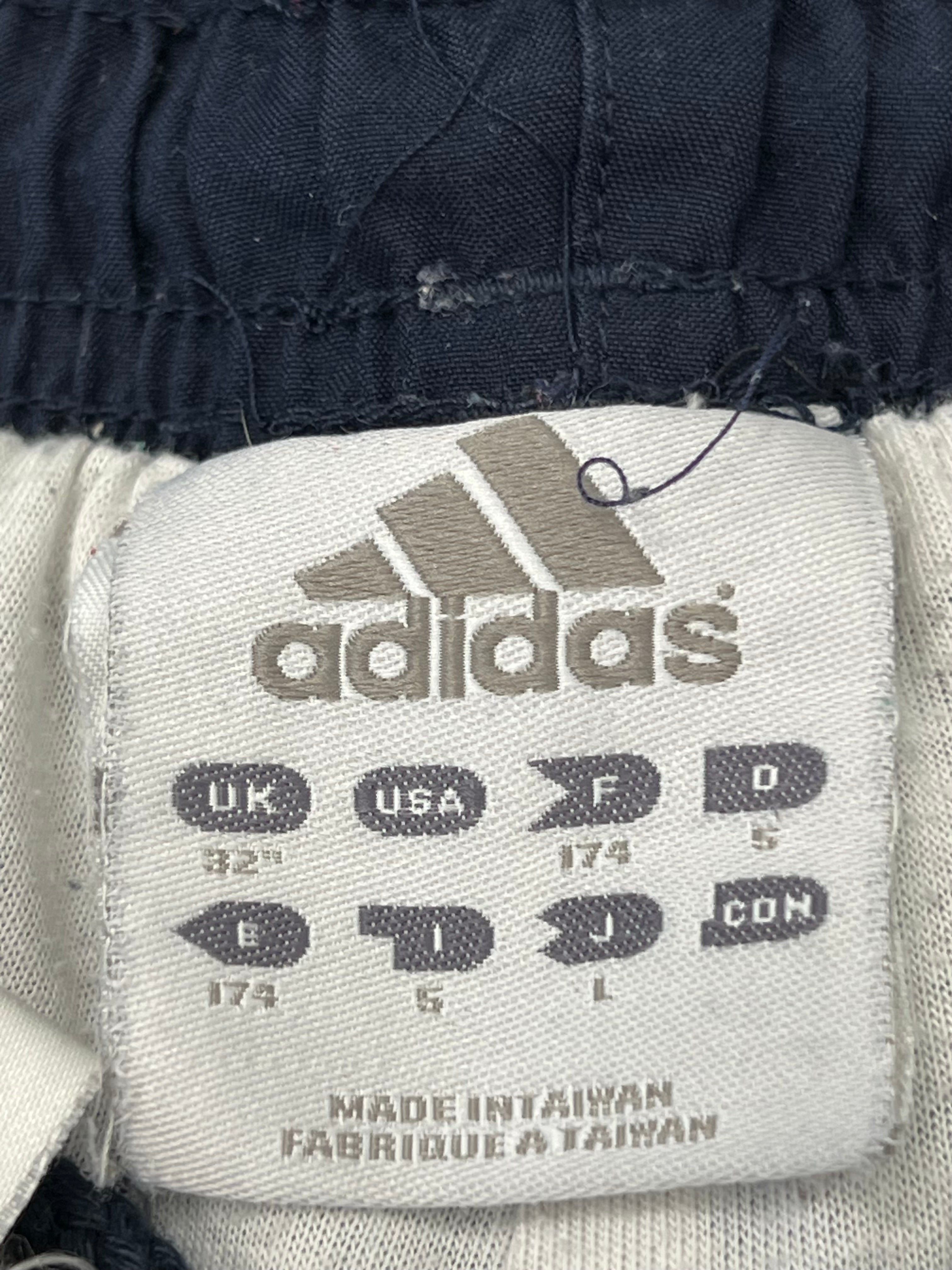 Close-up of Adidas branded label inside men's navy tracksuit bottoms indicating size UK 32 made in Taiwan