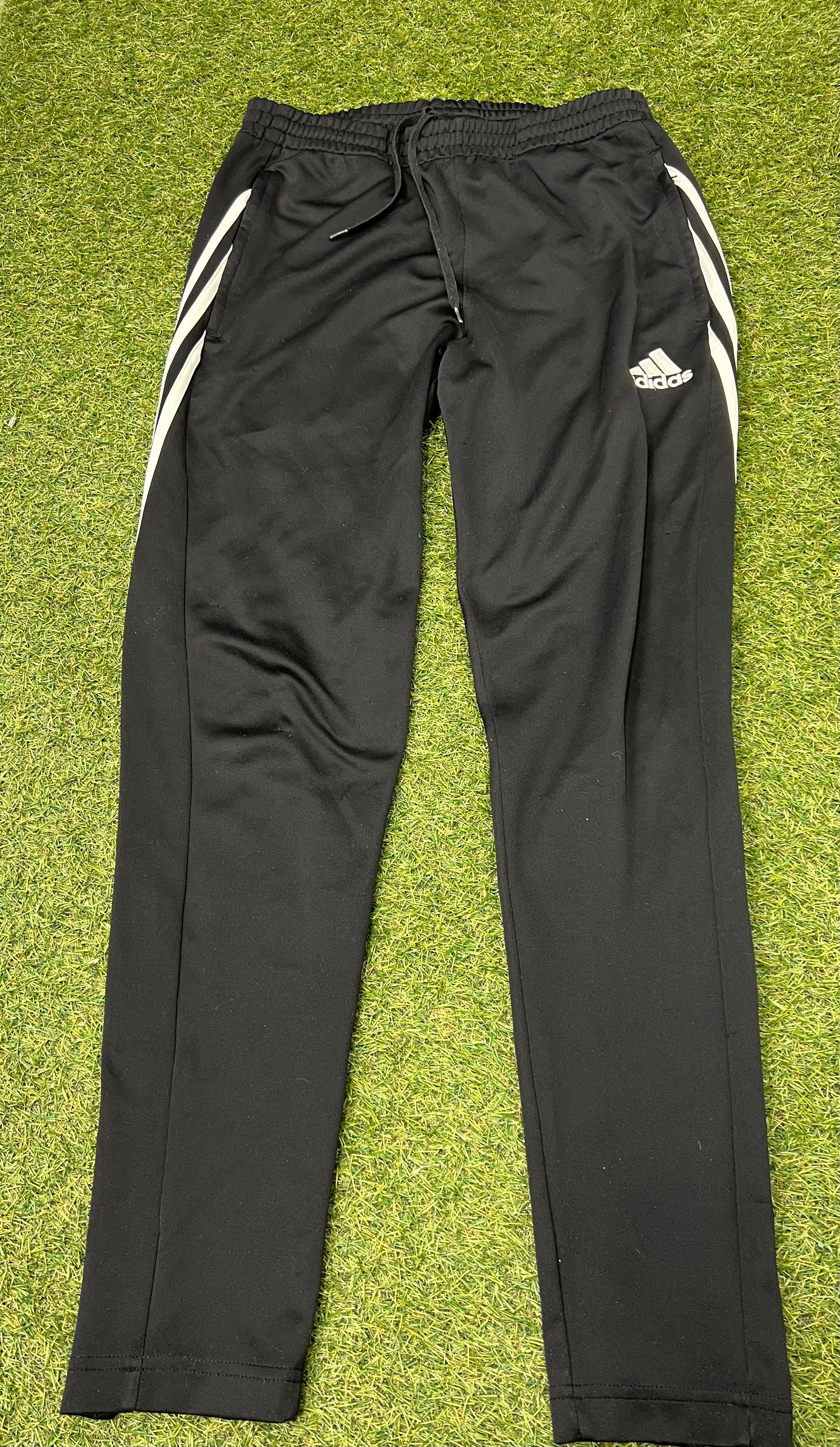 Adidas black tracksuit bottoms shown flat from front, featuring white three-stripe side detail and Adidas logo