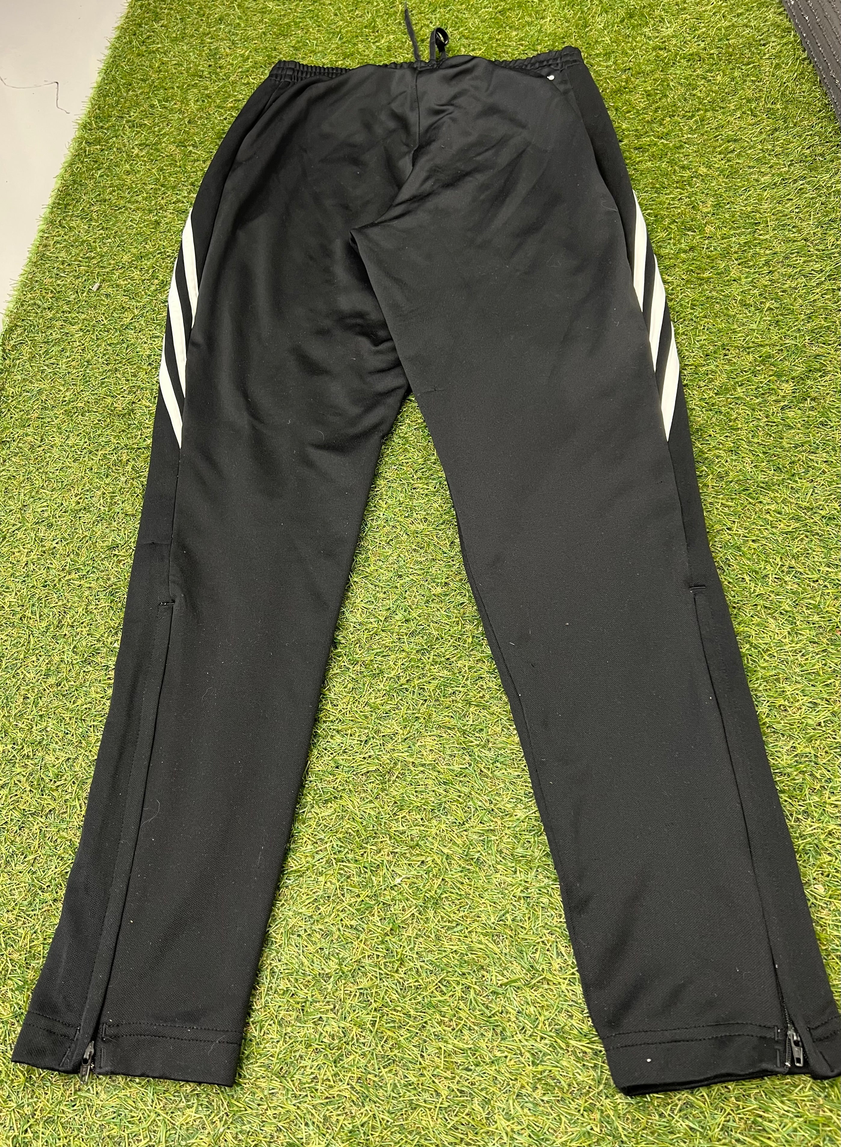 Close-up of black tracksuit bottom ankle zipper partially open, showing inner lining on grass
