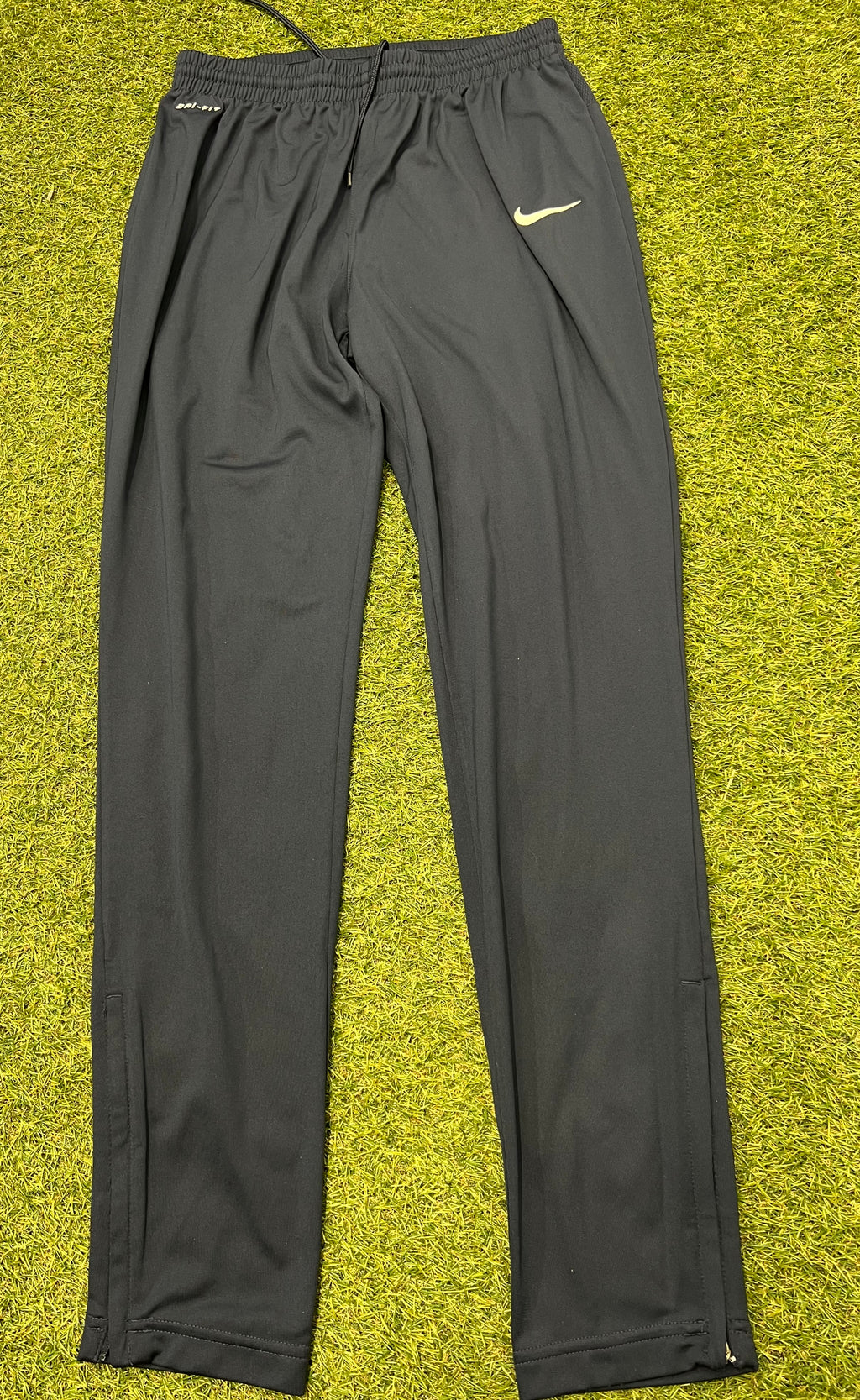 Front view of black Nike Dri-FIT tracksuit bottoms showing elastic waistband and logo