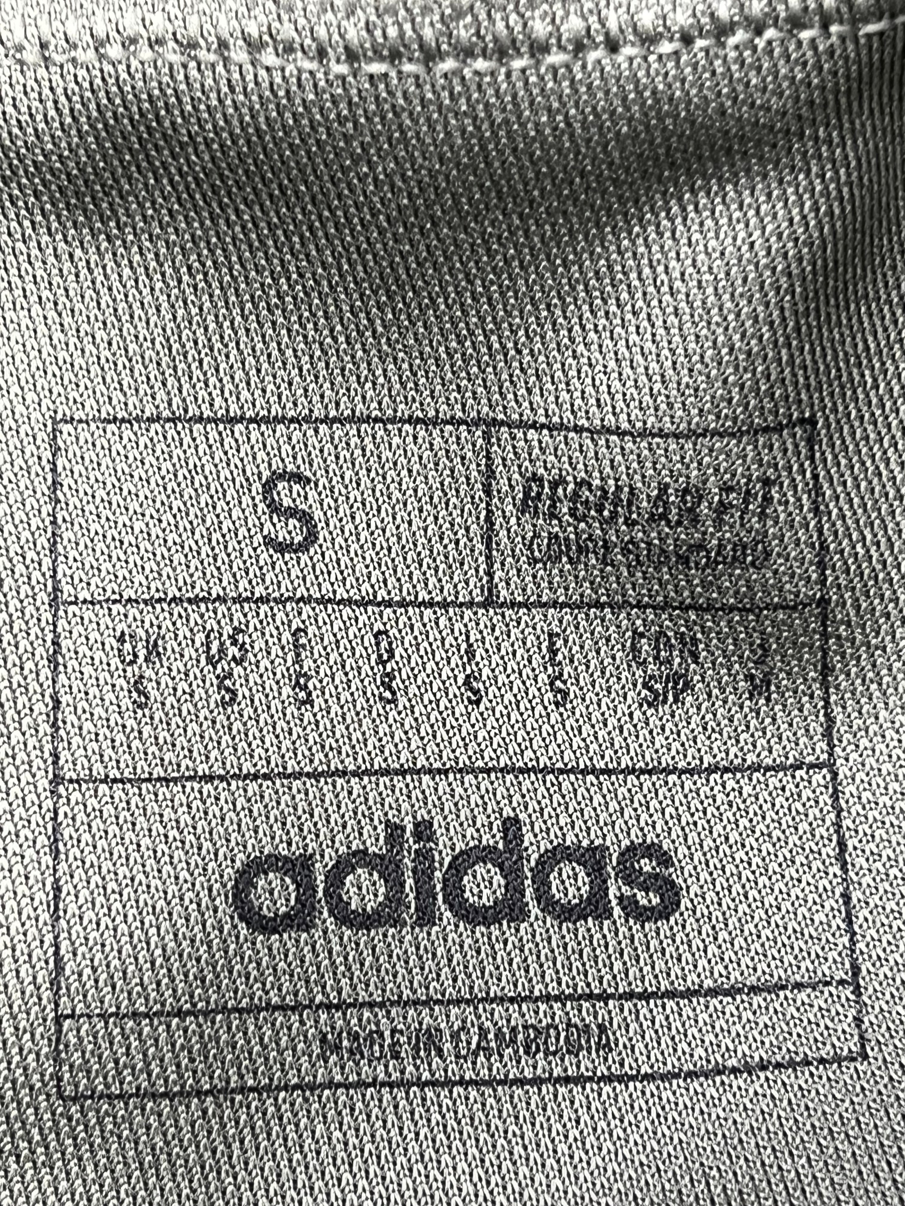 Close-up of interior label showing size small and adidas branding on khaki tracksuit bottoms.