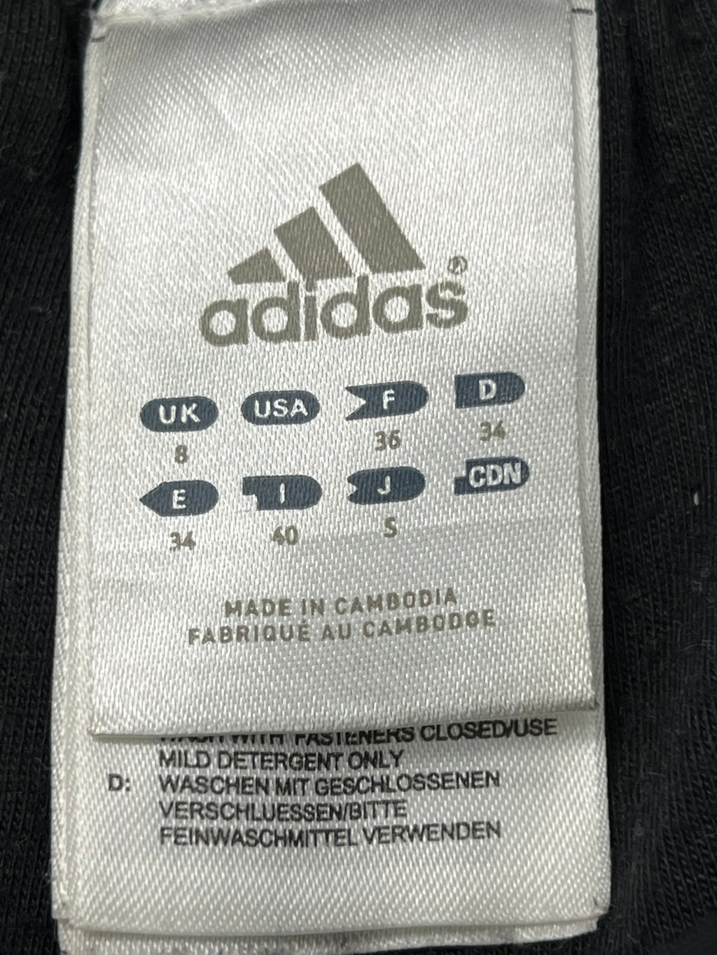 Close-up of adidas label showing size details and manufacturing information on the inside of the tracksuit bottoms