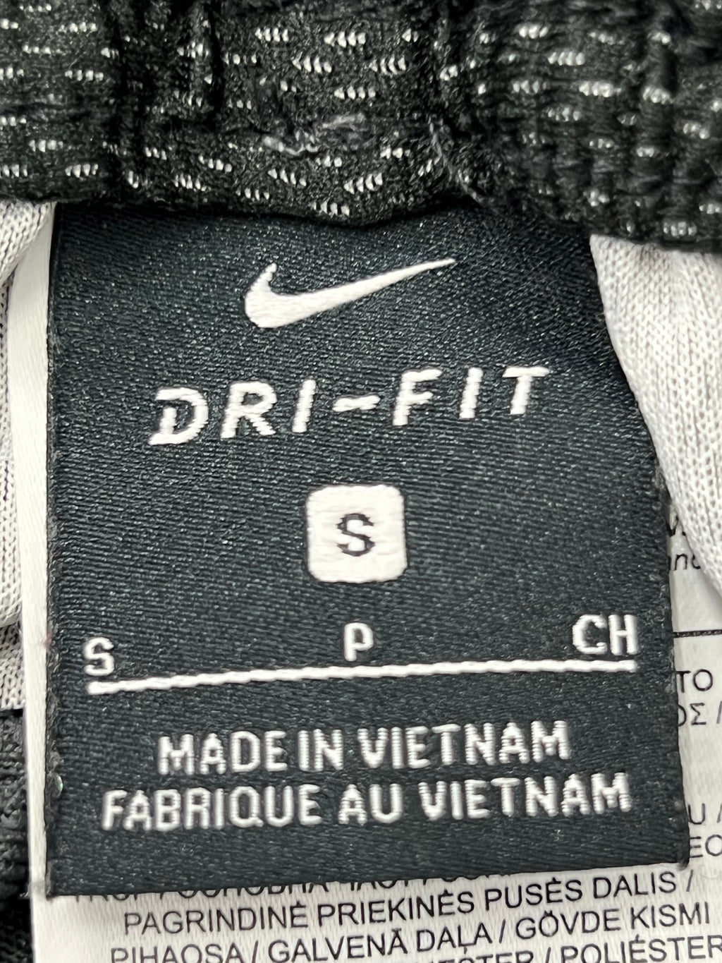 Close-up of black care label inside Nike Dri-FIT tracksuit trousers showing size small and made in Vietnam