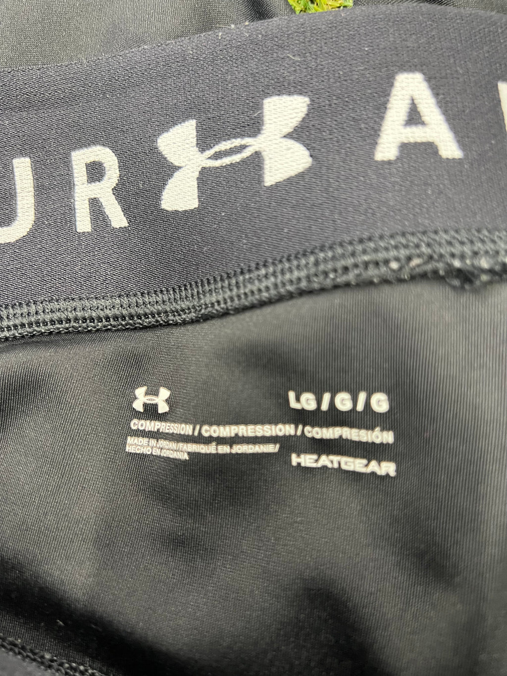 Close-up of inside waistband showing Under Armour logo, size LG, compression and HeatGear technology printed on black fabric