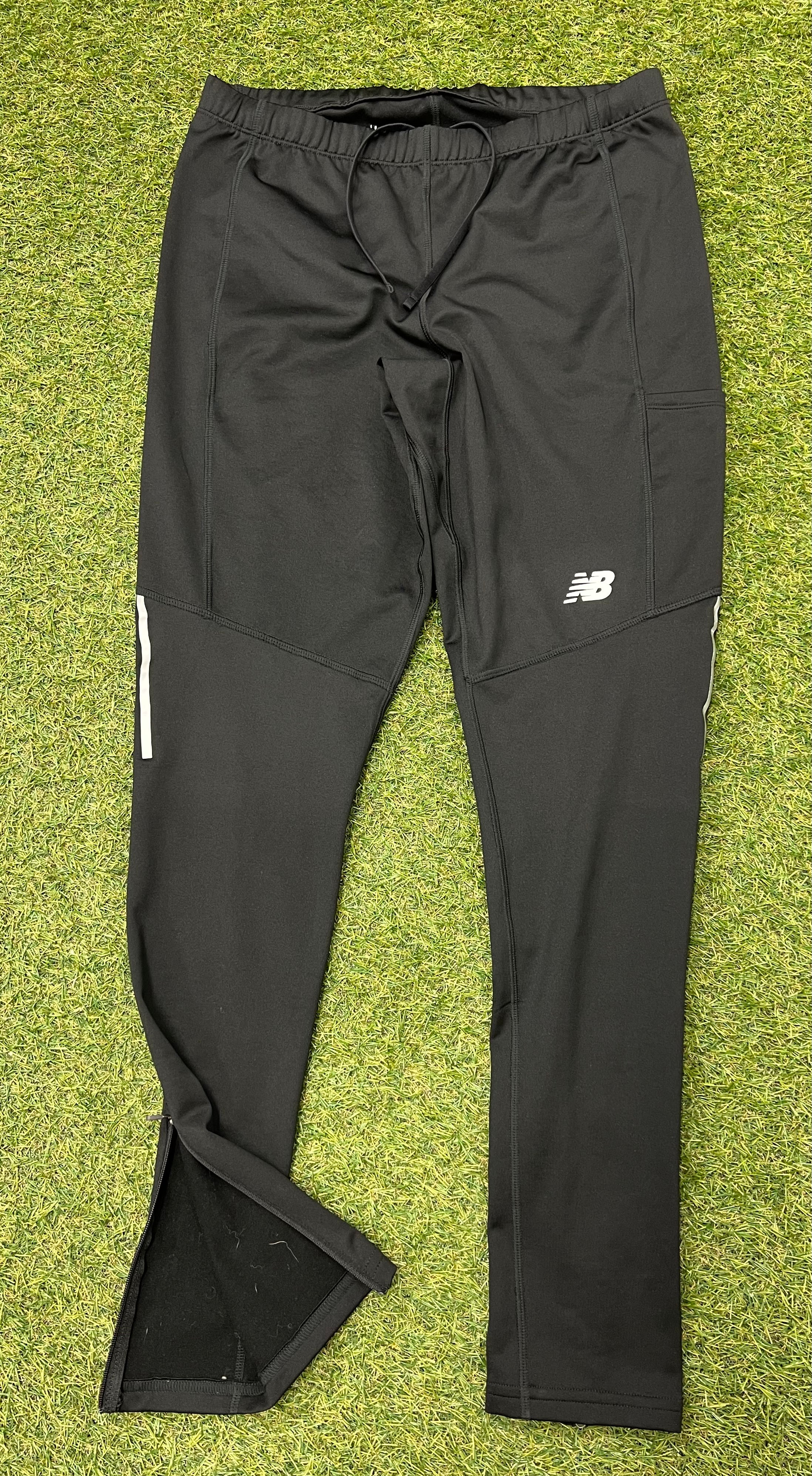 Front view of black New Balance running trousers with elastic waistband and reflective detailing on side