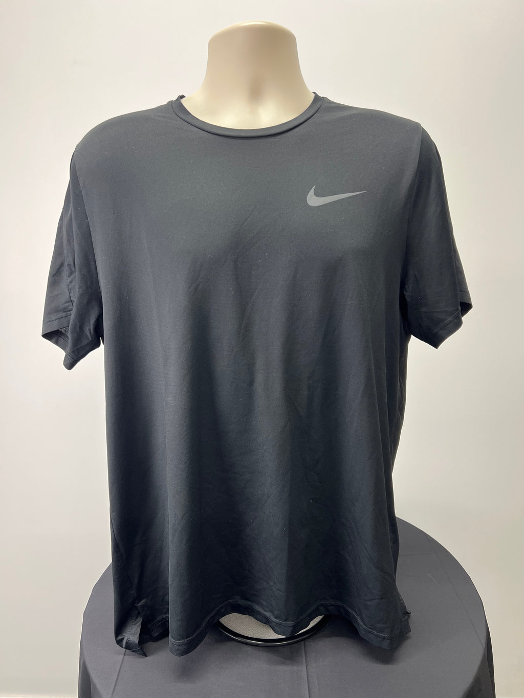 Front view of a black Nike Dri-FIT t-shirt on a mannequin with a subtle reflective Nike logo on the chest
