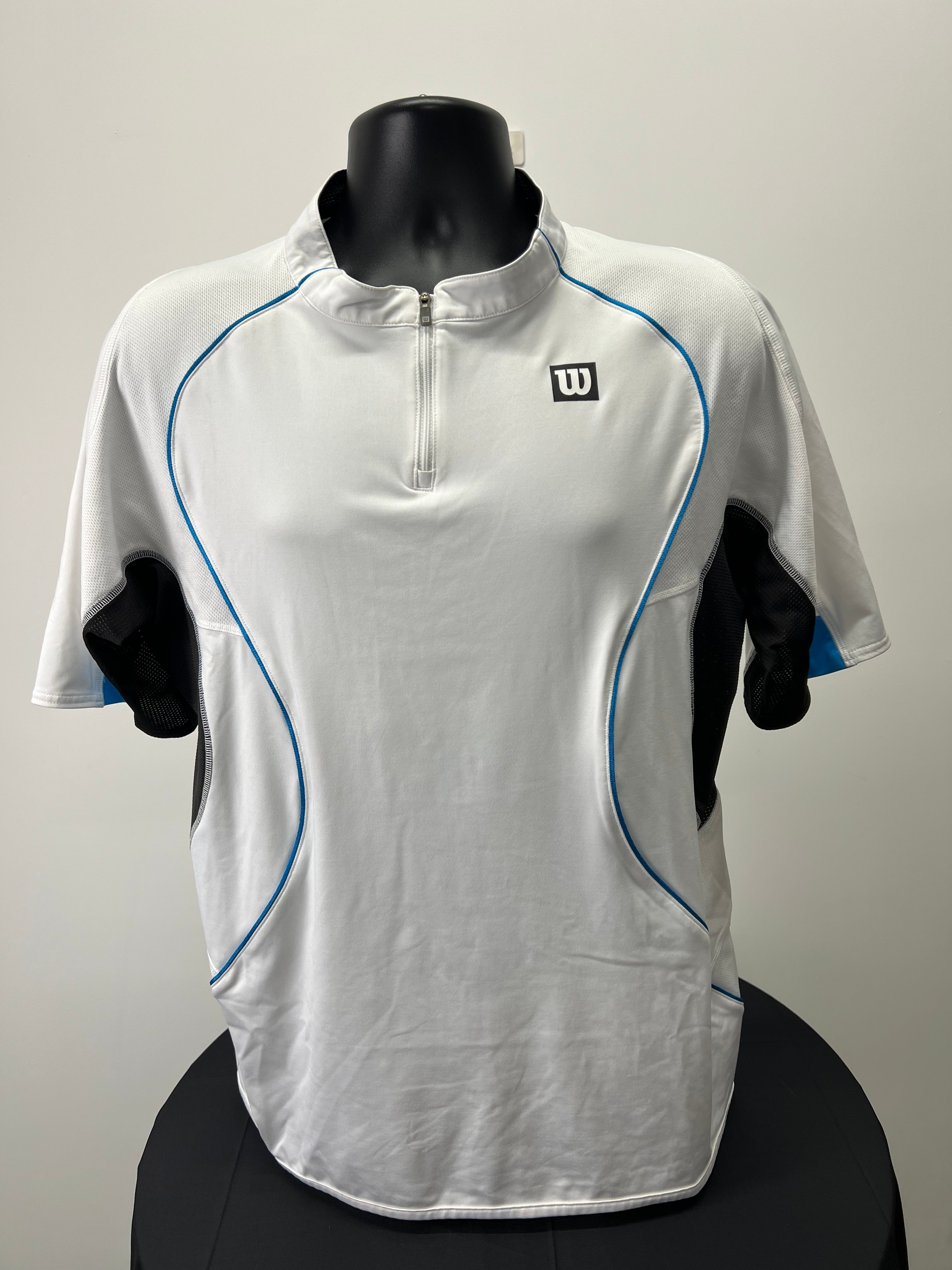 Front view of men's Wilson white 1/4 zip tennis top with blue piping and black mesh side panels on mannequin