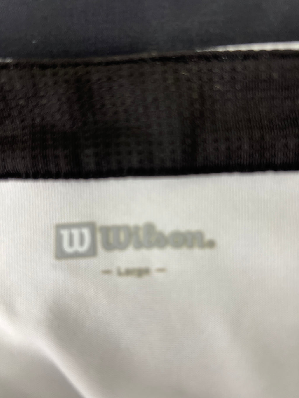 Close-up of Wilson logo and size label printed inside men's tennis top