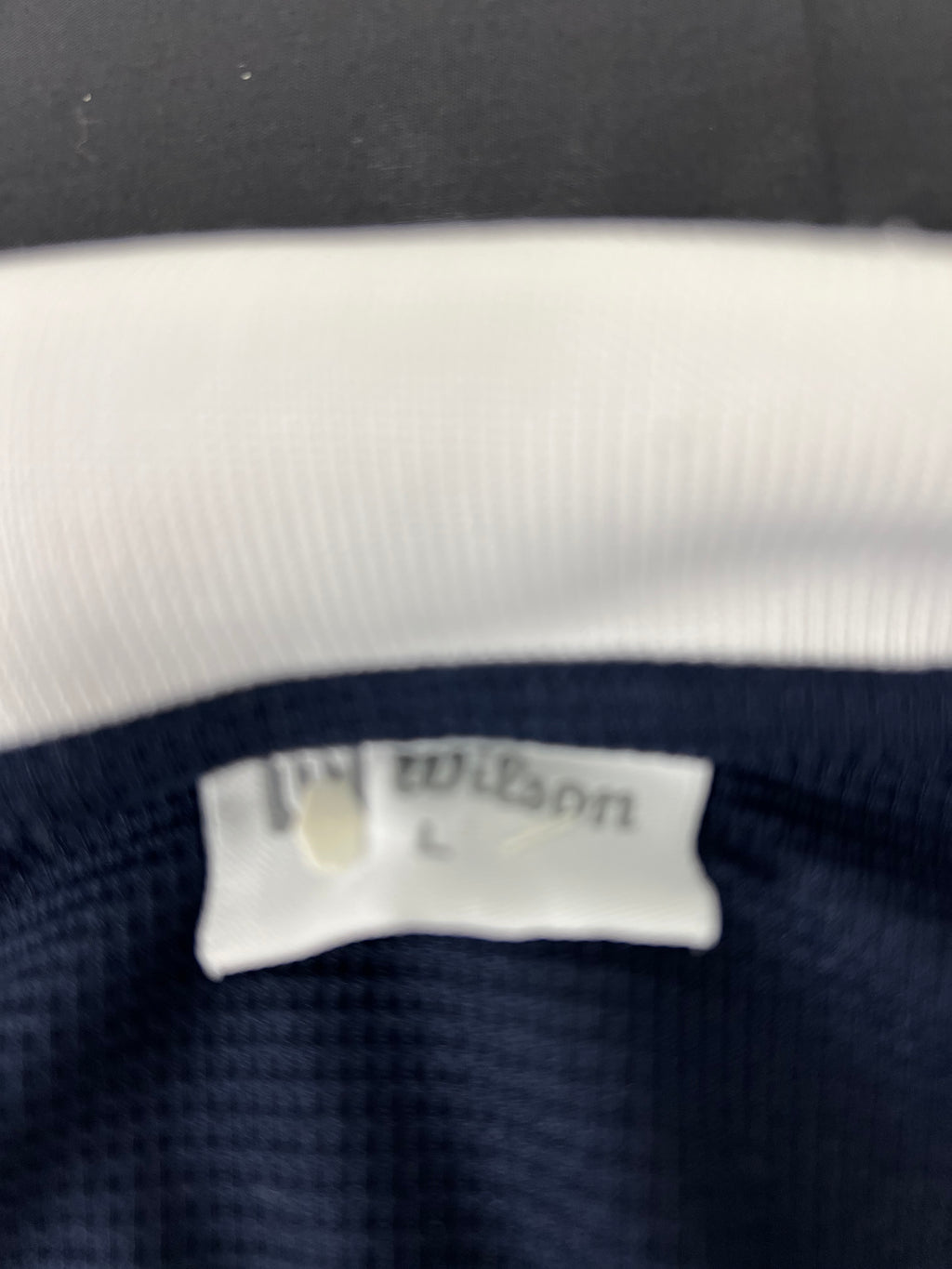 Close-up of Wilson brand tag inside men's polo shirt indicating size large