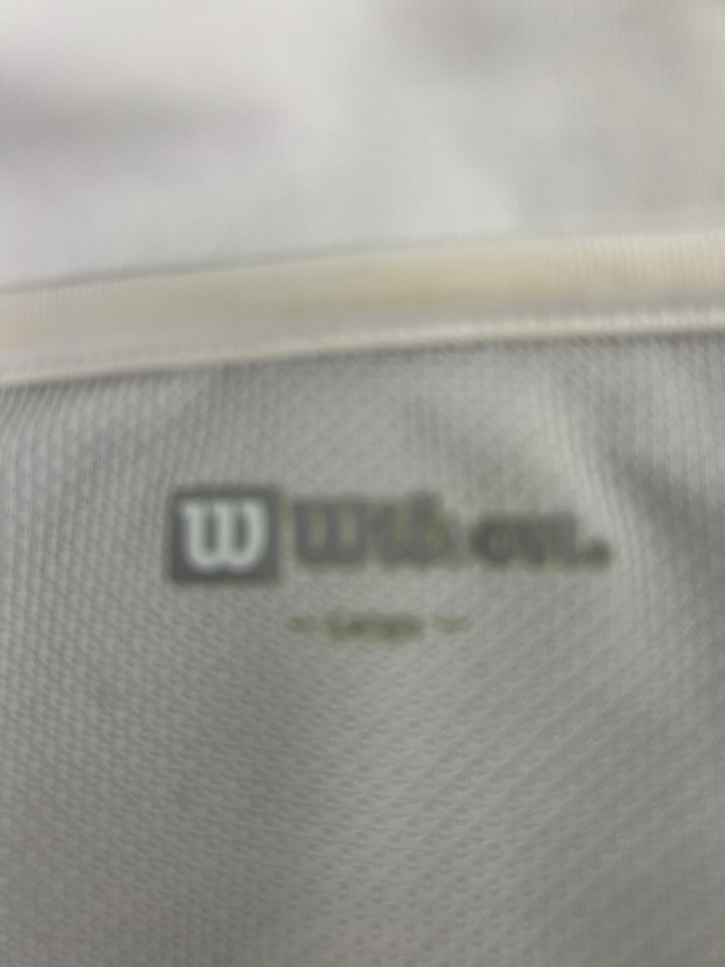 Close-up of the inner label showing Wilson brand logo on men's performance polo