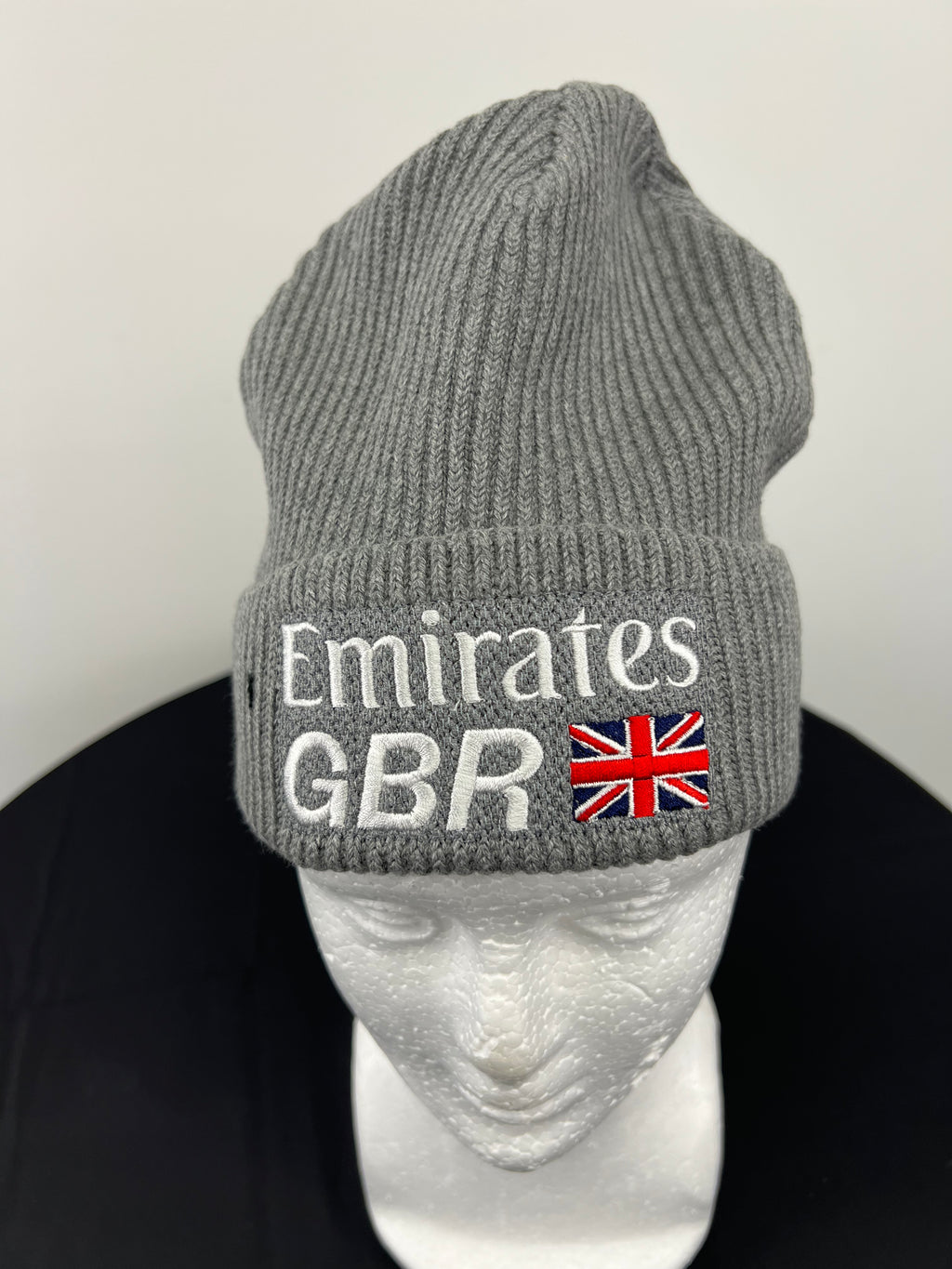 Front view of grey ribbed knit beanie hat with White Emirates GBR logo and British flag embroidery on cuff displayed on a white mannequin head