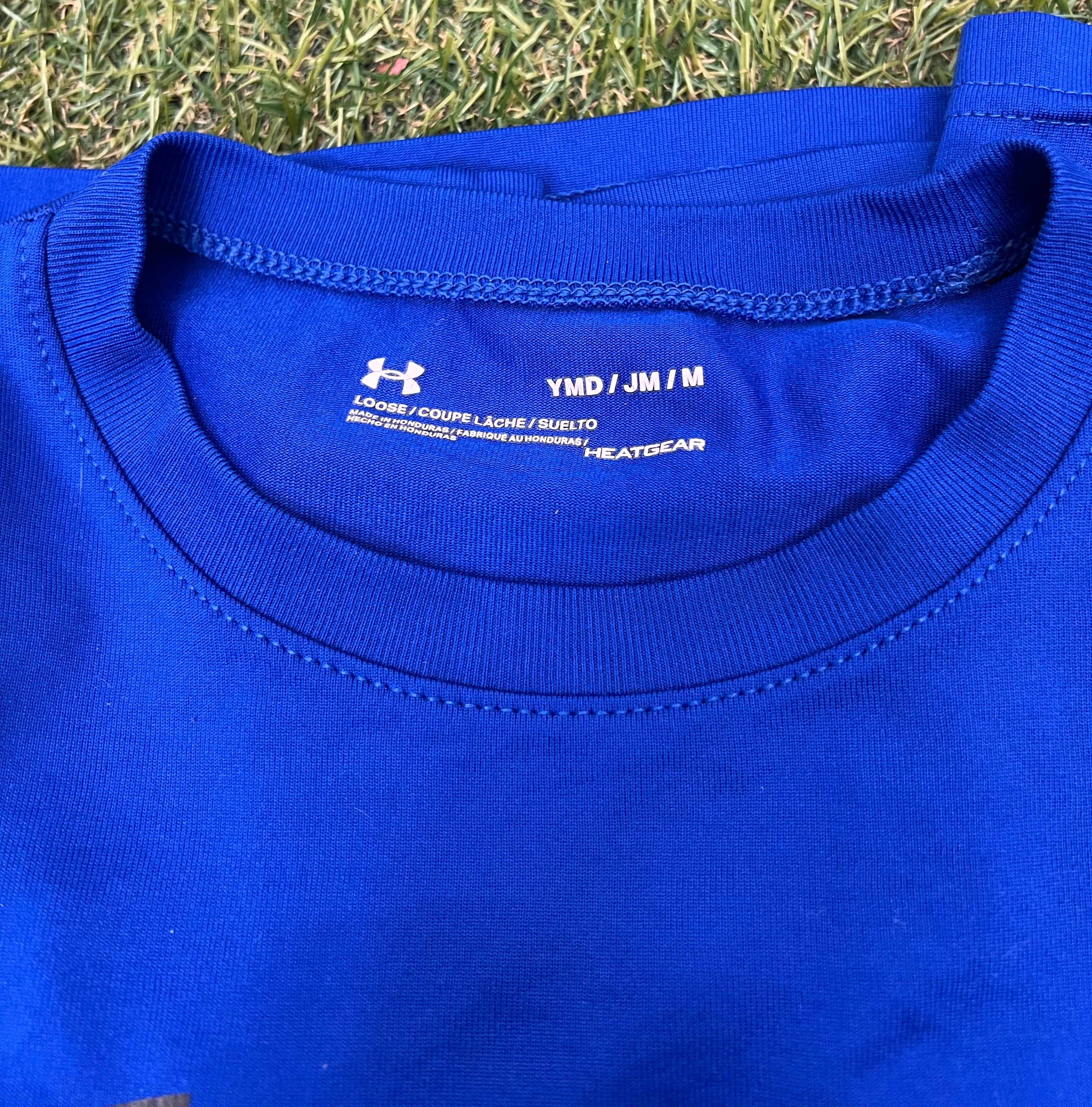 Close-up view of blue Under Armour kids T-shirt neckline showing HeatGear fabric and loose fit label