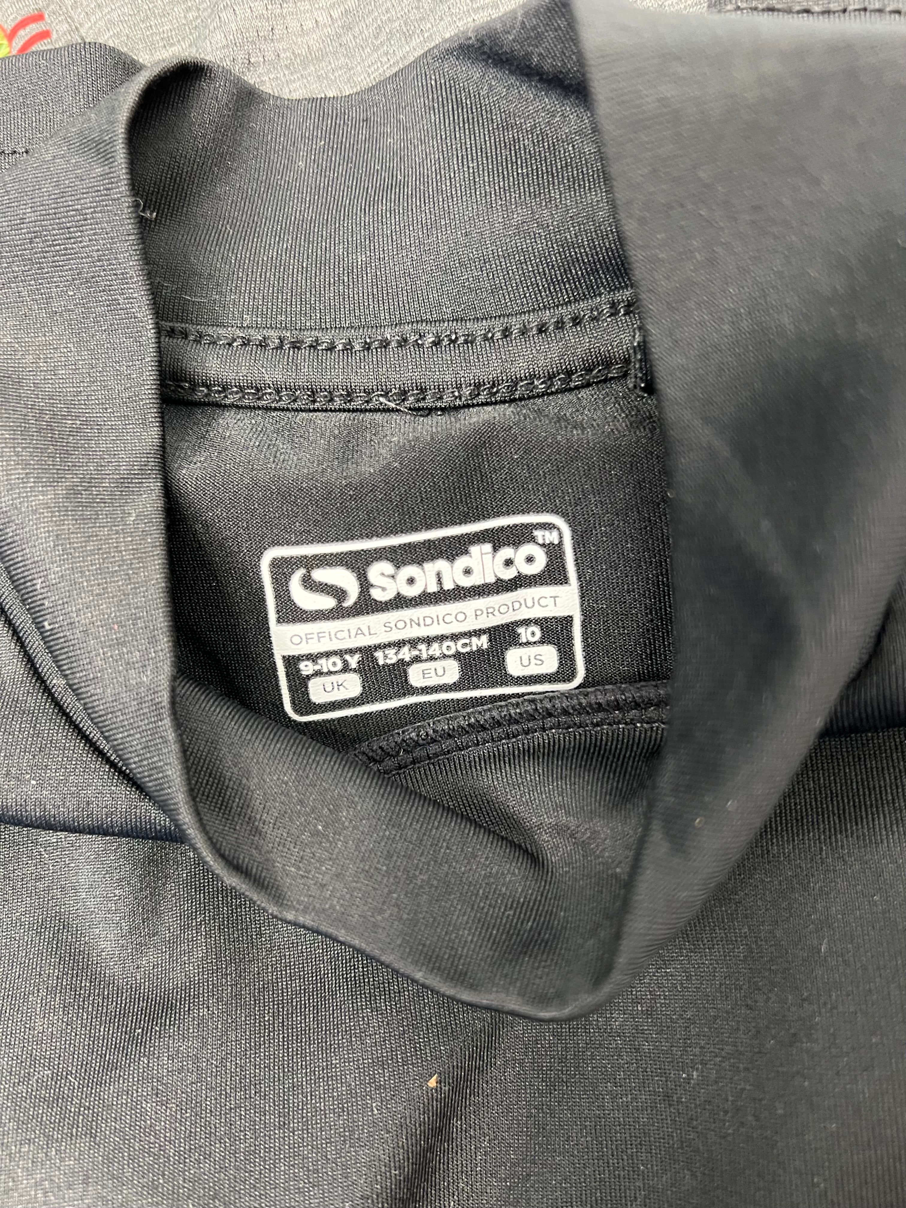 Close-up of black Sondico kids top label indicating size 9-10 years and official product branding