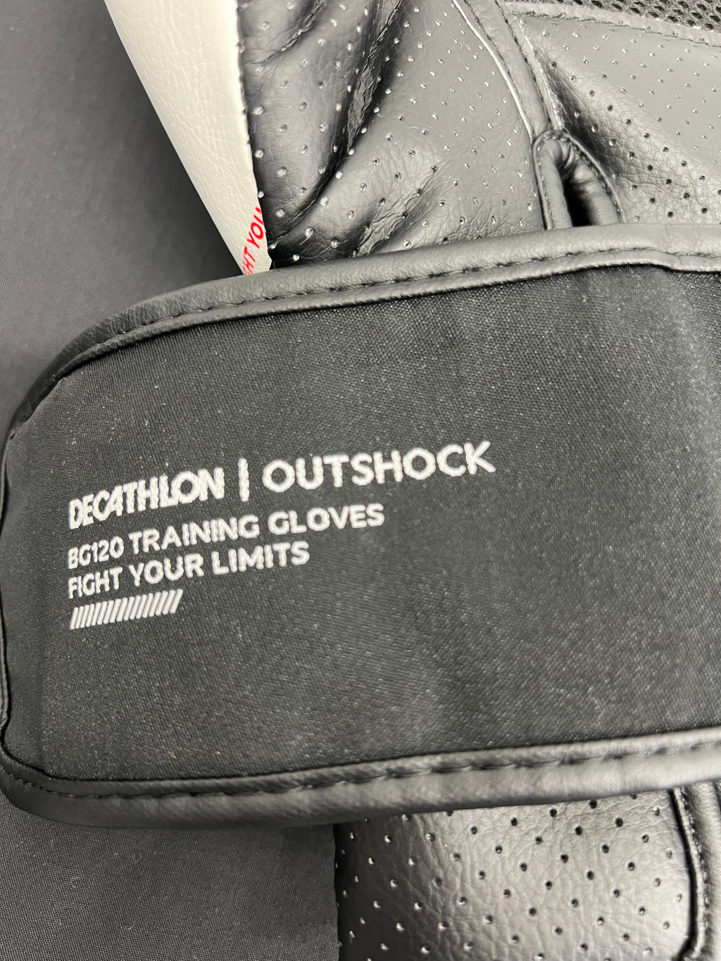 Close-up of Outshock label on black wrist strap of boxing glove with training details