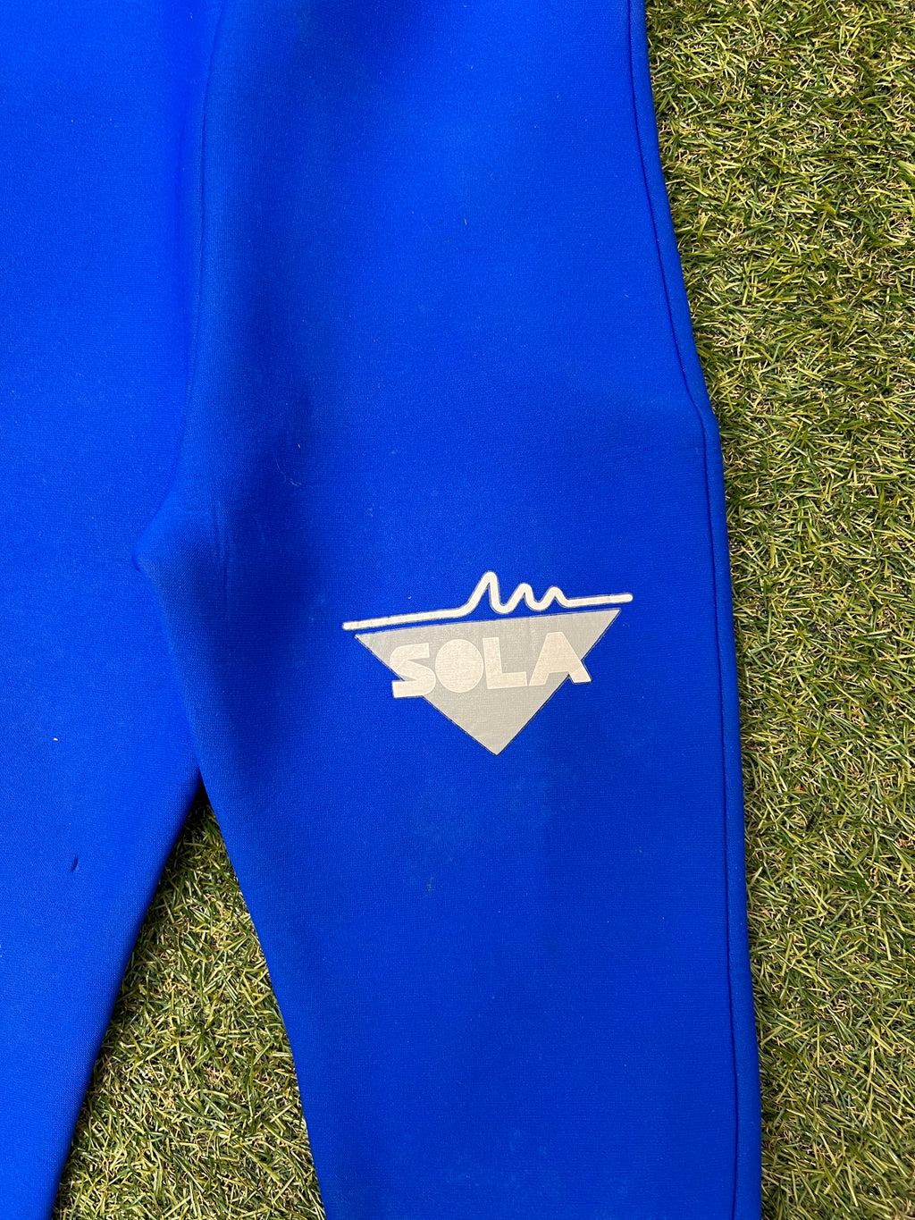 Close-up of Sola logo printed in white on the blue section of the wetsuit leg