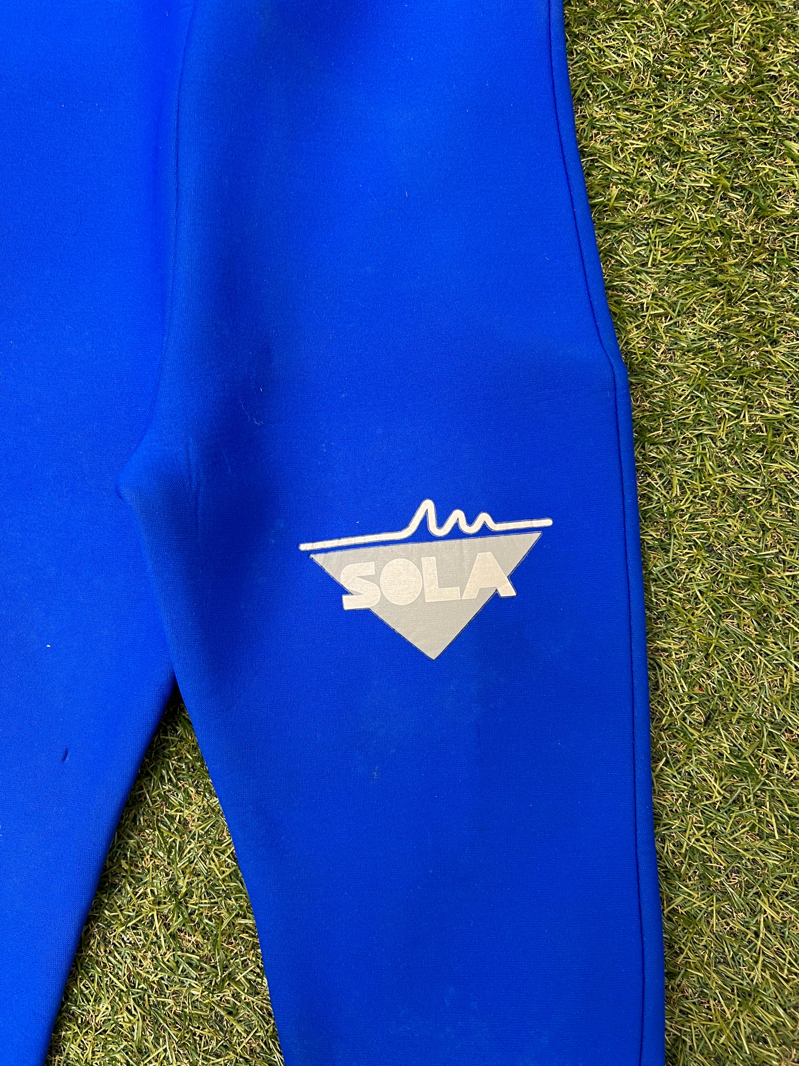 Close-up of Sola logo printed in white on the blue section of the wetsuit leg