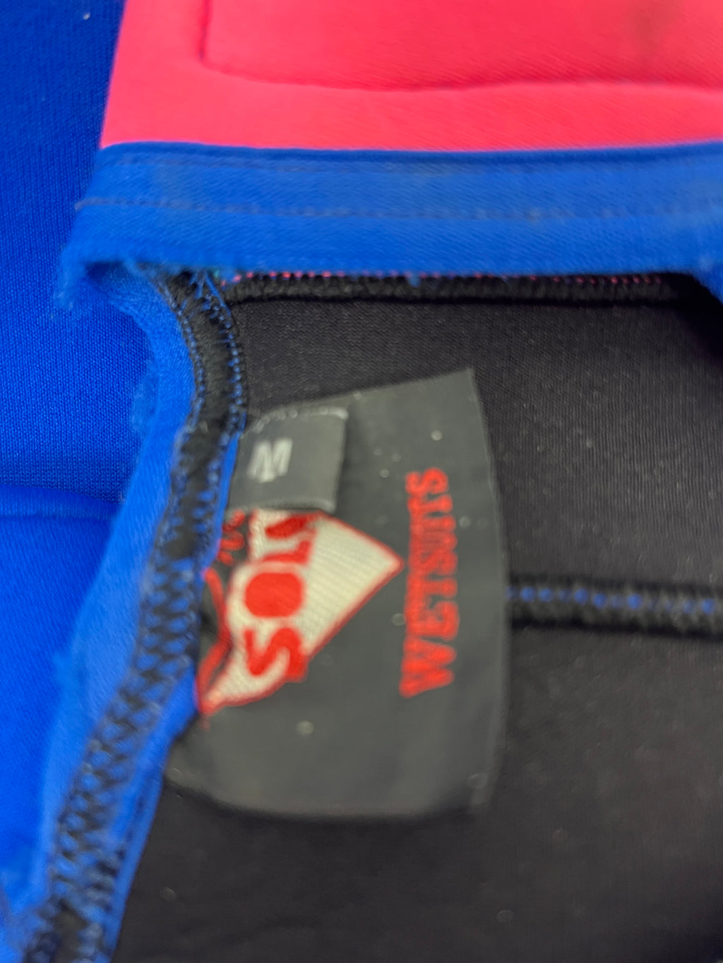 Close-up of Sola wetsuit size label inside the garment showing size M