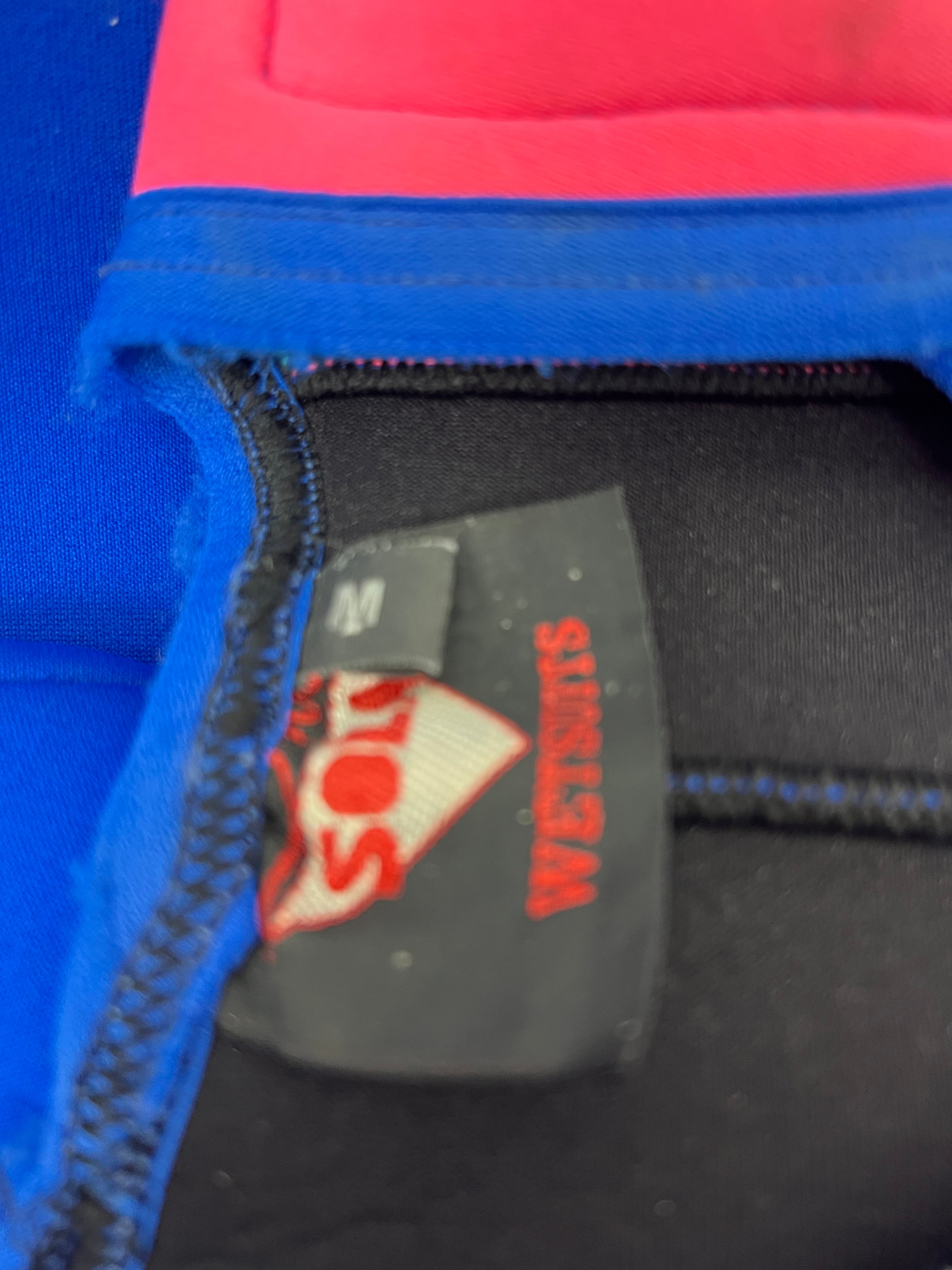 Close-up of Sola wetsuit size label inside the garment showing size M