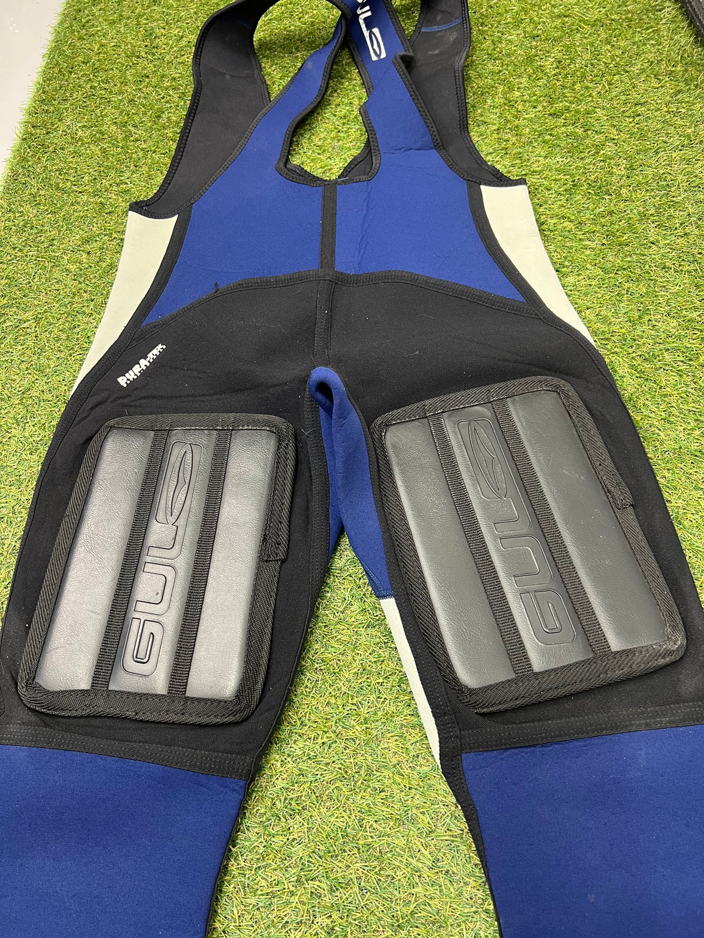 Detailed rear view of knee padding with Gul logos on black neoprene sections of sleeveless wetsuit bib trousers