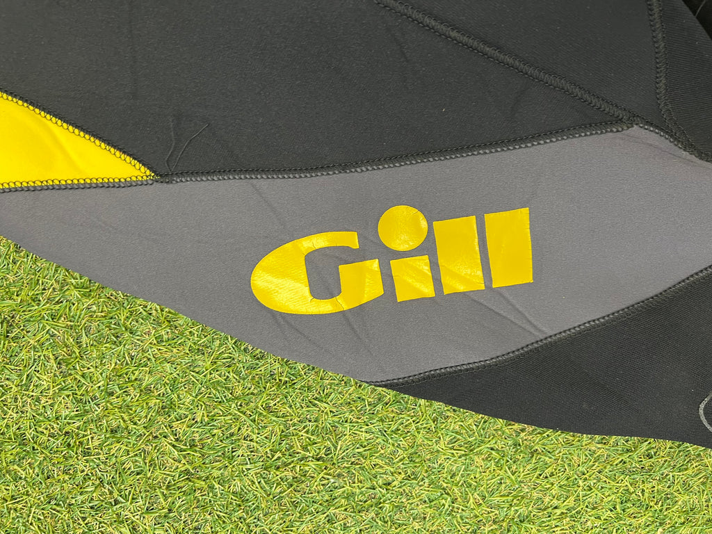 Close-up of yellow Gill logo on grey fabric panel of wetsuit