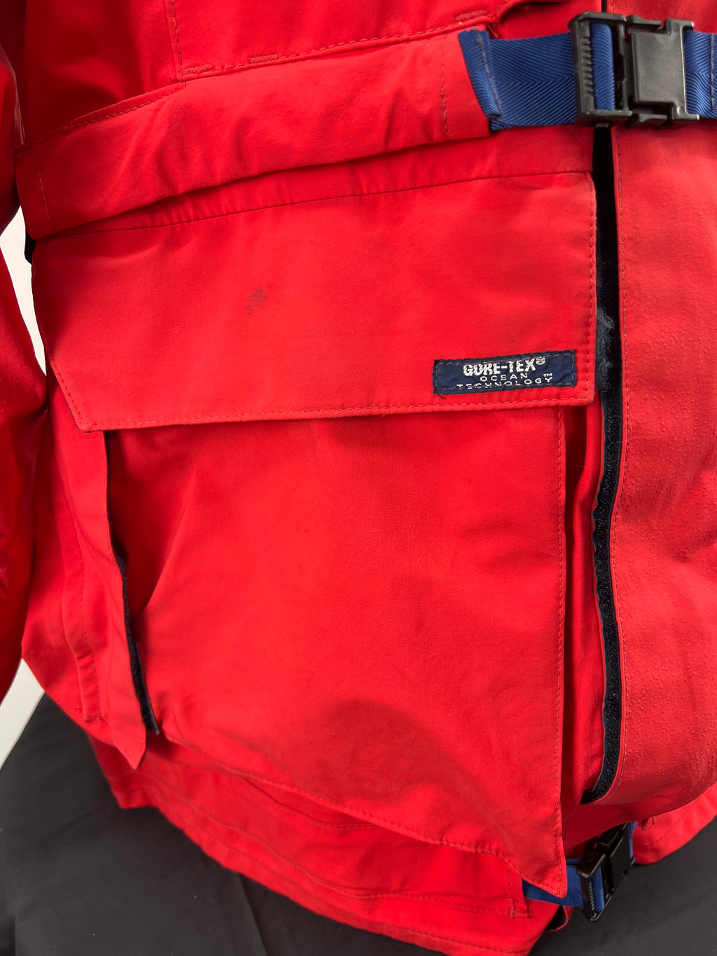 Close-up of pocket flap showing GORE-TEX Ocean Technology label on red jacket