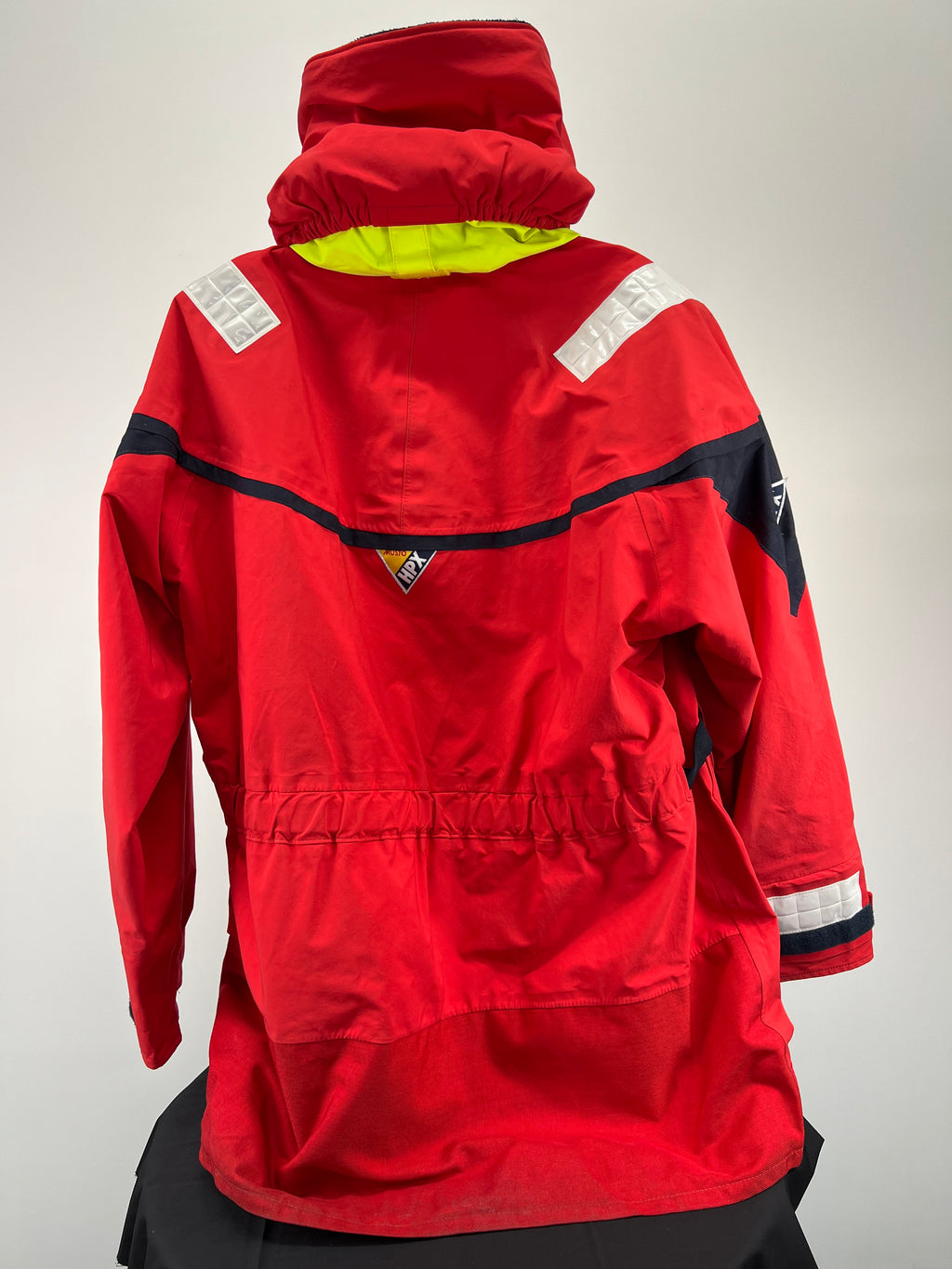 Back view of red Musto HPX sailing jacket with adjustable elastic waist and reflective panels