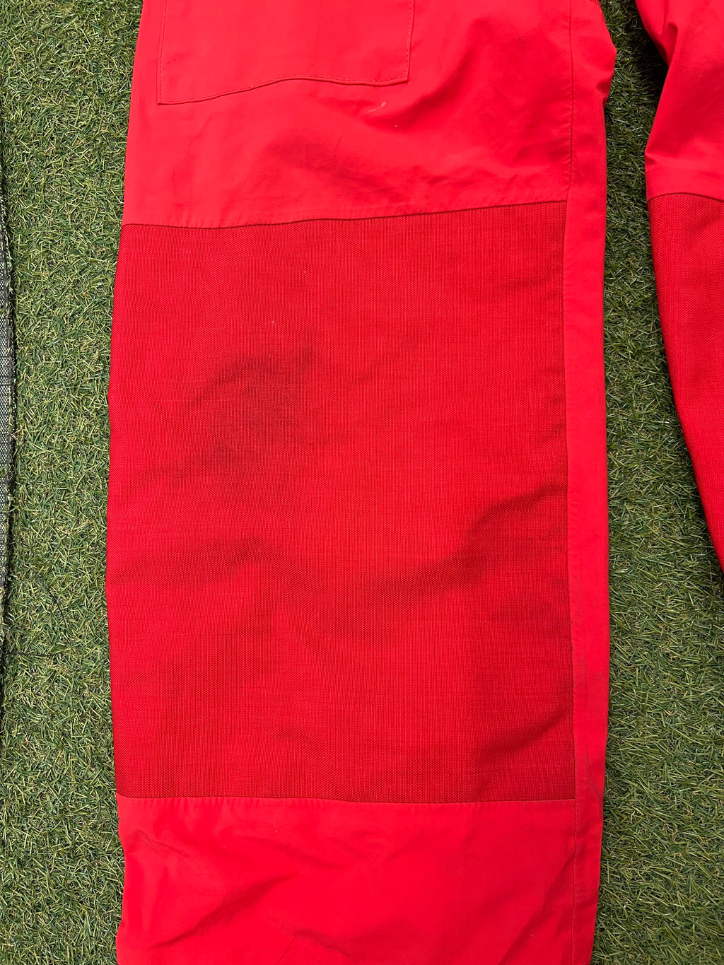 Close-up of red reinforced knee patch on sailing trousers showing sturdy Cordura fabric.
