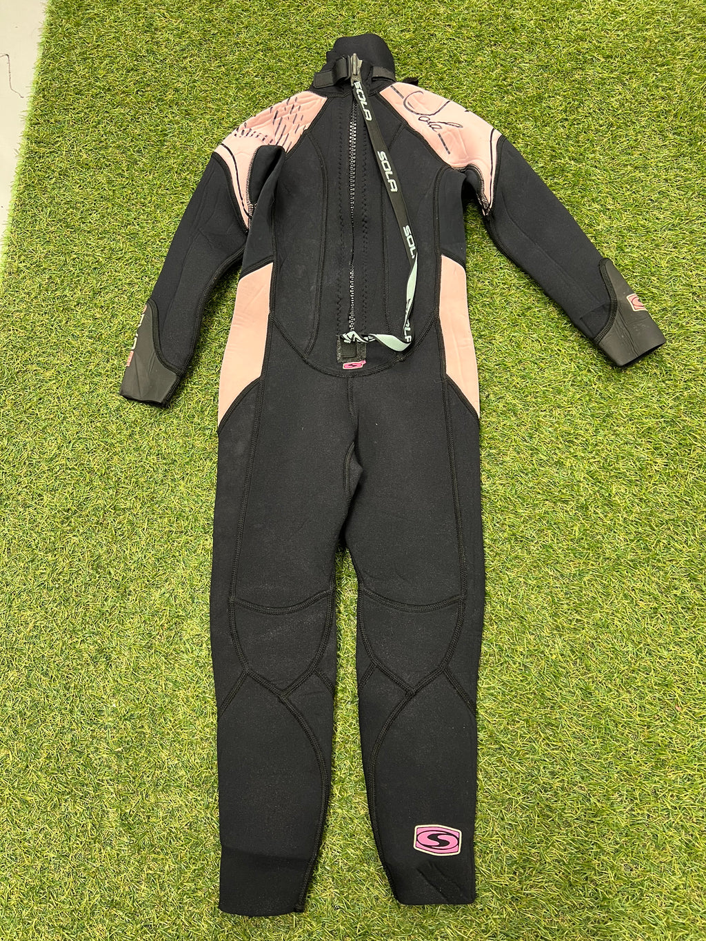 Back view of kids Sola wetsuit showing black base with pink shoulder panels and long back zipper with pull cord