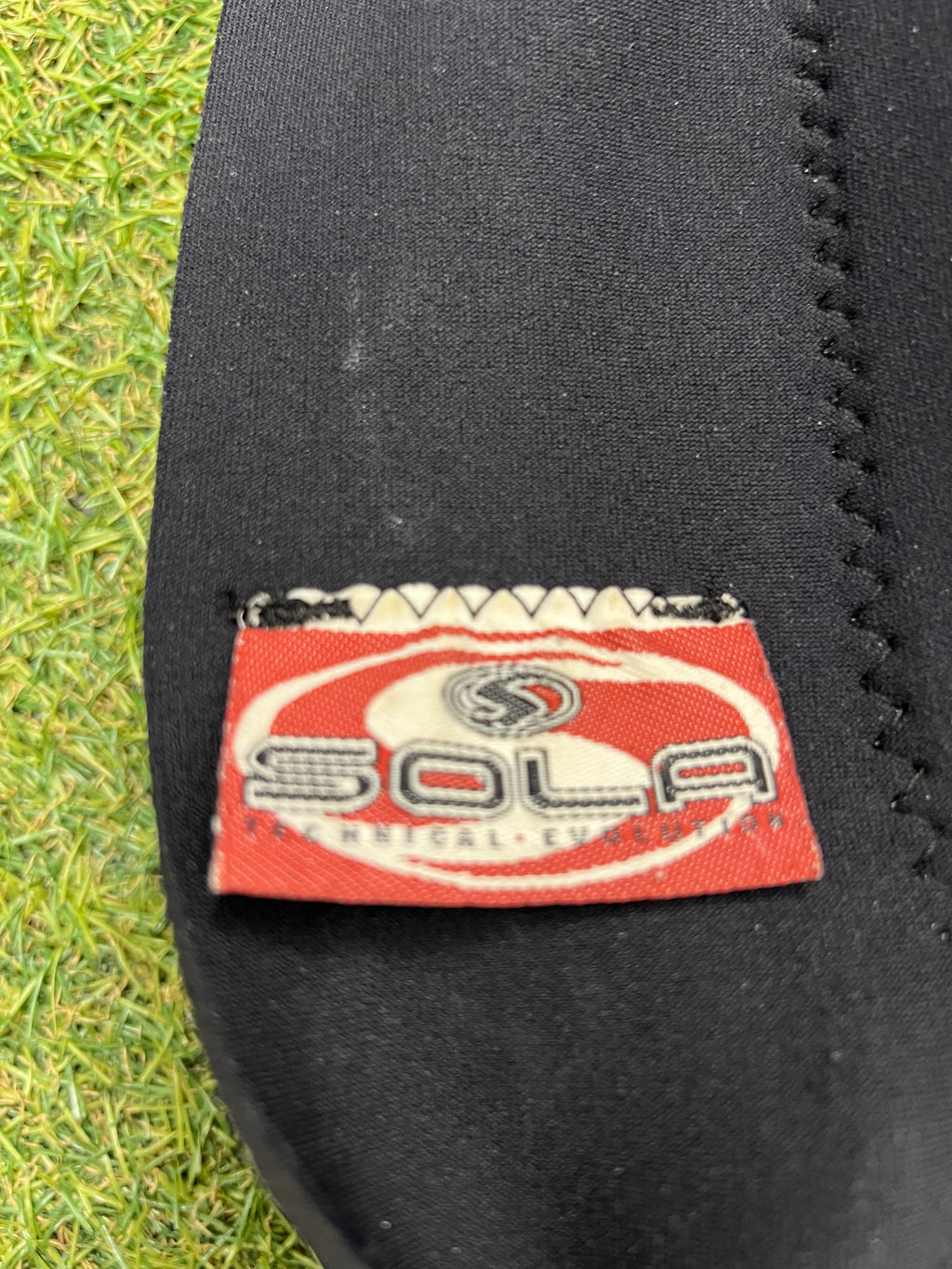 Close-up of red and white Sola brand label stitched on wetsuit black neoprene material