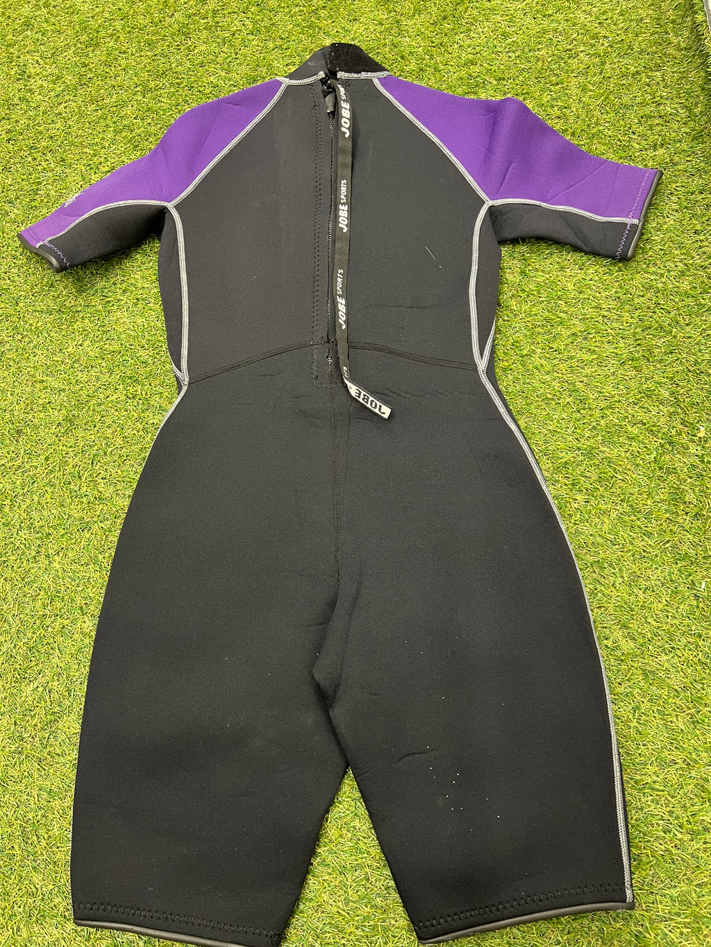Back view of Jobe kids short sleeve wetsuit showing back zipper with pull cord on grass surface