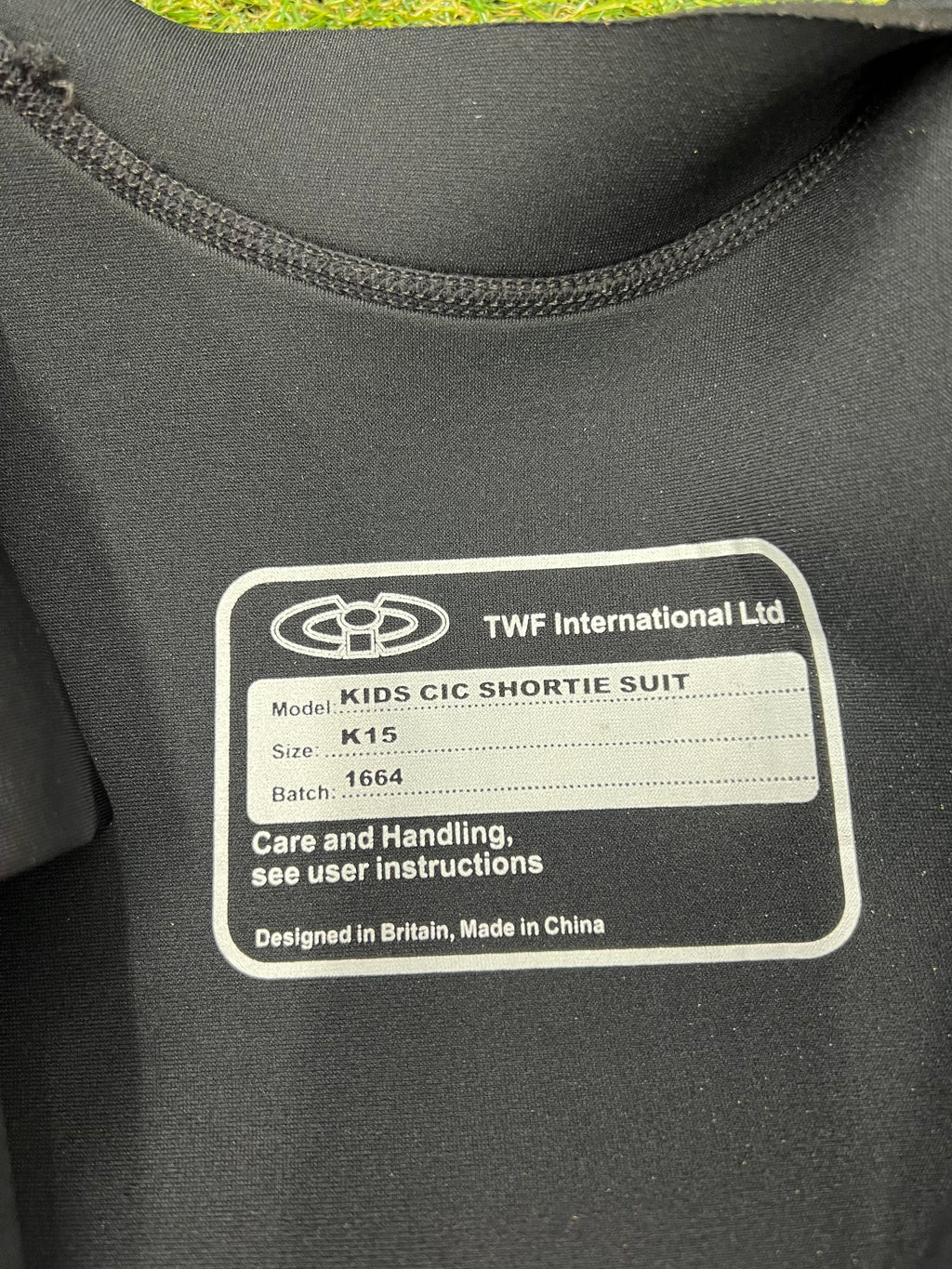 Close-up of inside label of CIC kids shortie wetsuit indicating model K15 and care instructions