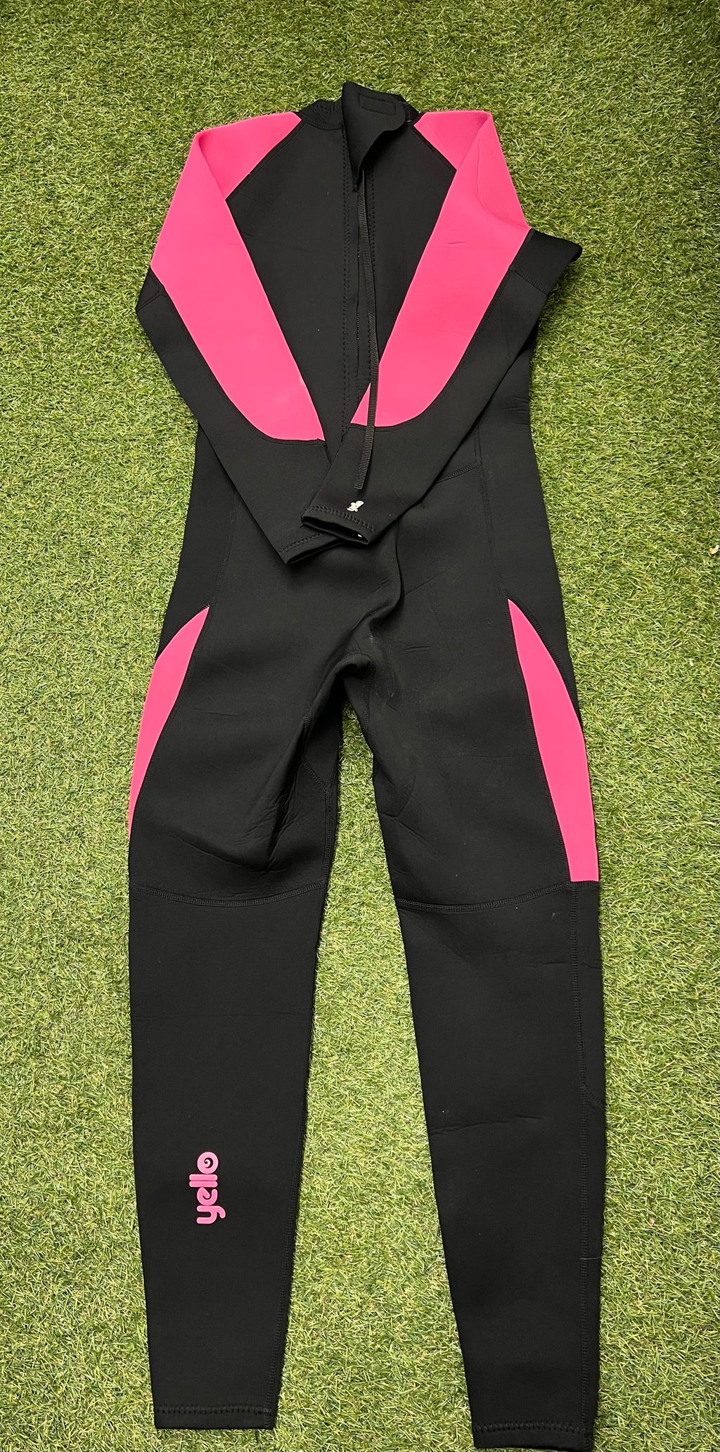 Back view of the wetsuit showing zipper closure and pink side panels on black neoprene material