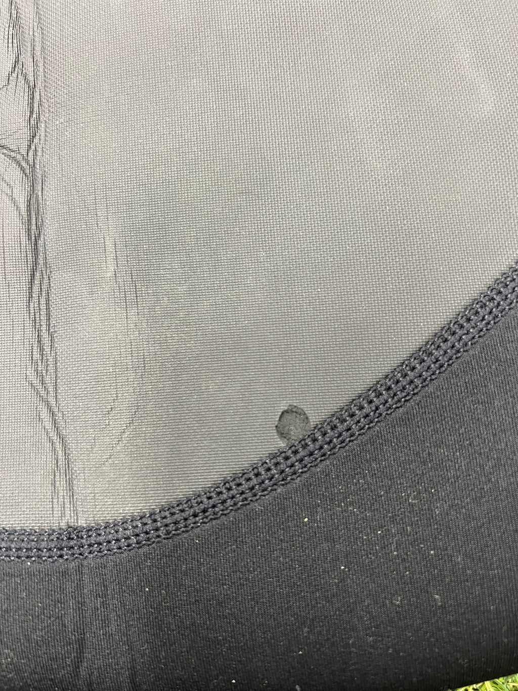 Detailed close-up of the wetsuit fabric showing textured neoprene and reinforced stitching