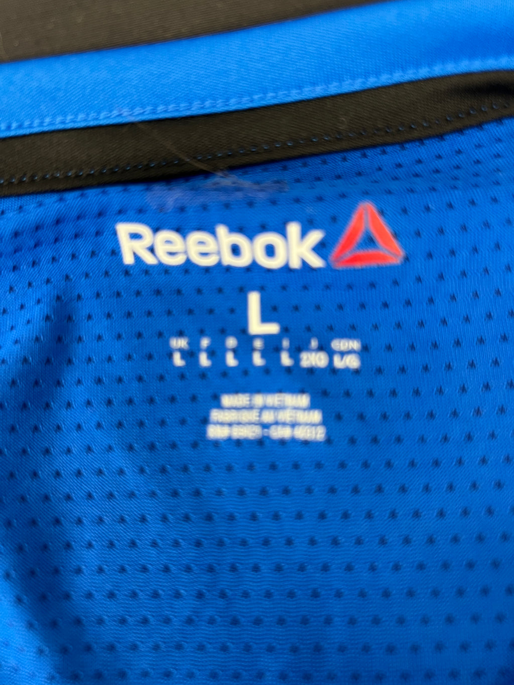 Close-up of the inner neck label on men's Reebok sleeveless top showing size large and manufacturing details