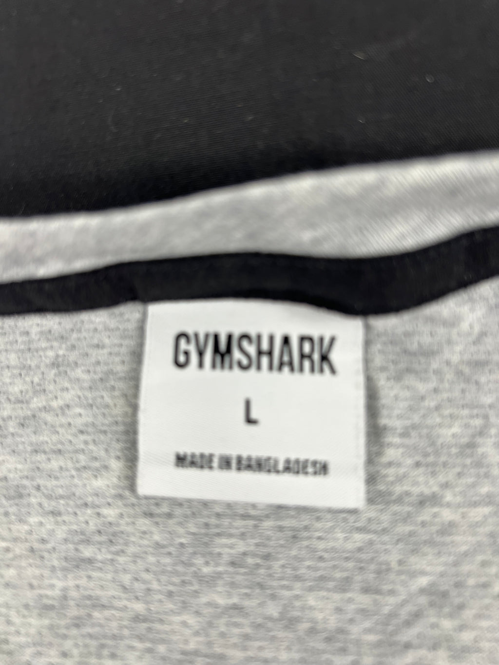 Close-up of Gymshark label inside grey sleeveless top showing size Large