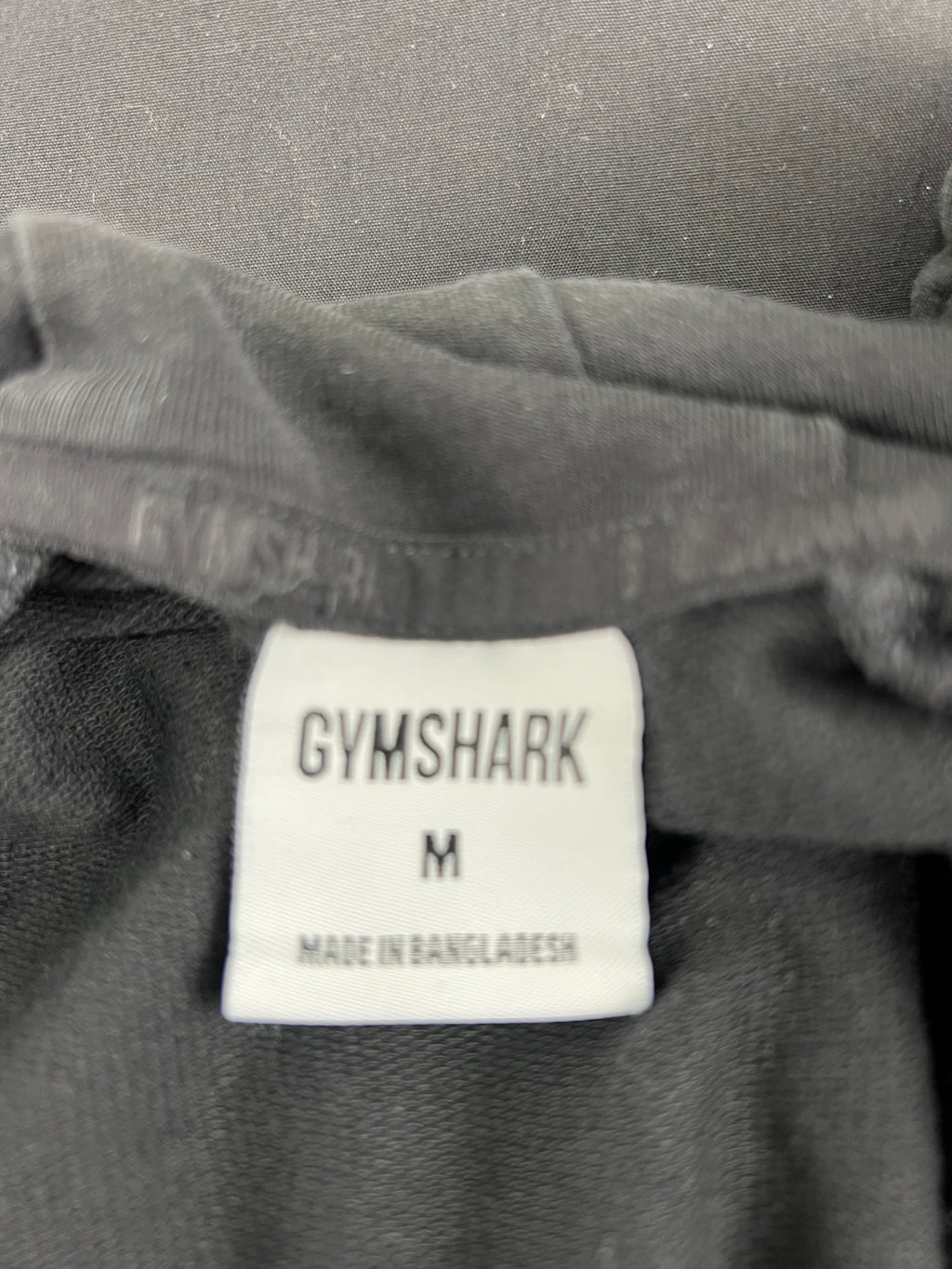Close-up of the white Gymshark label indicating size medium and made in Bangladesh
