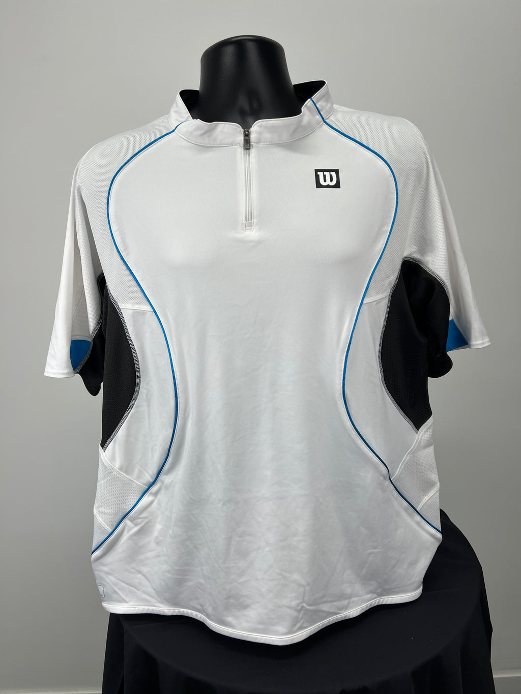 Front view of Wilson white sports top with black and blue details and 1/4 zip on black mannequin