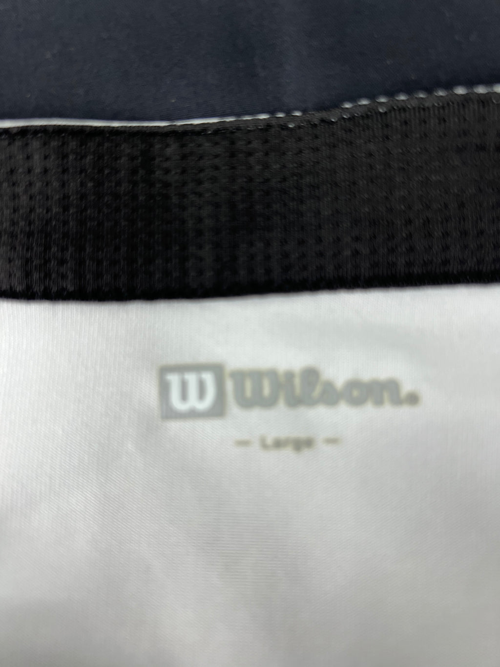 Close-up of Wilson logo and size label printed inside the collar of the sports top