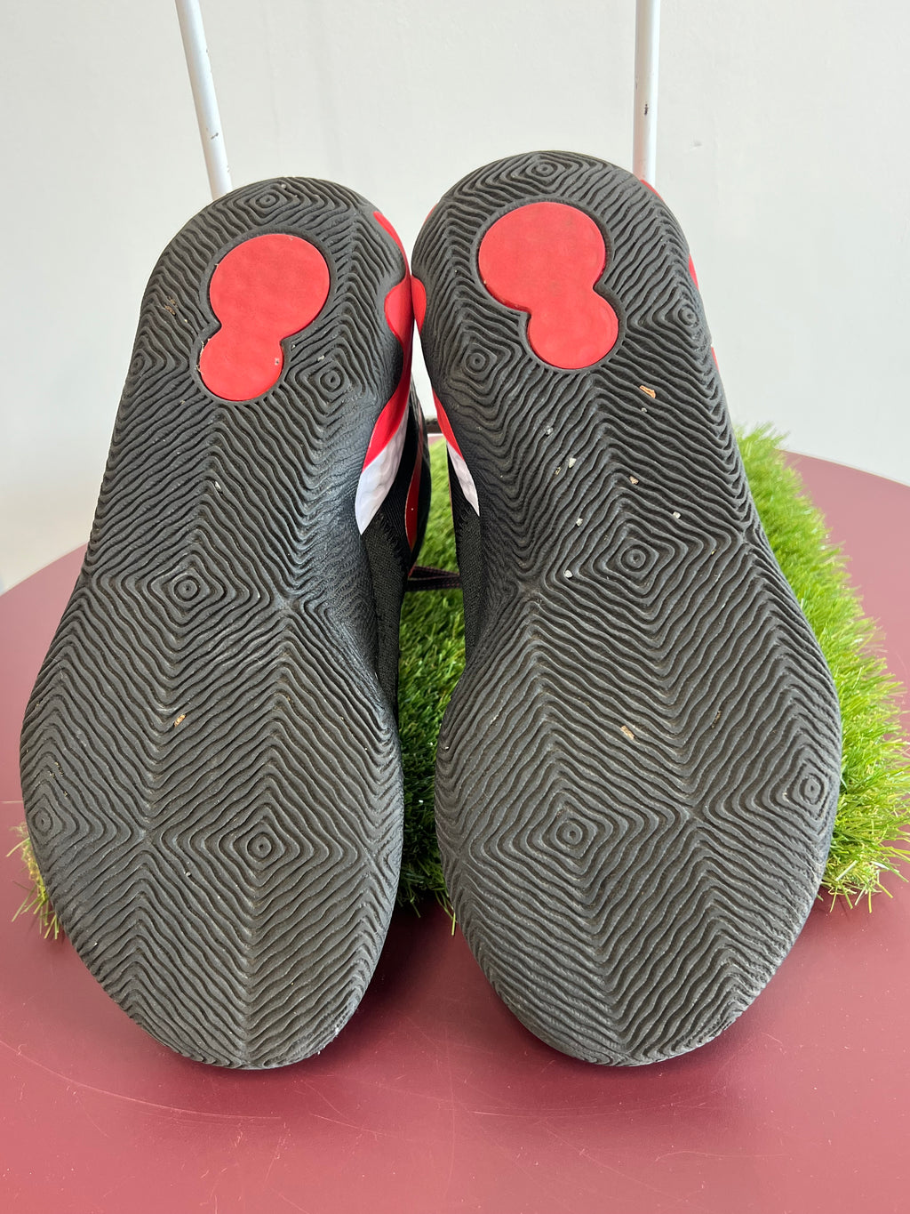 Sole view of Nike Renew Elevate trainers with wavy traction pattern in black and red rubber