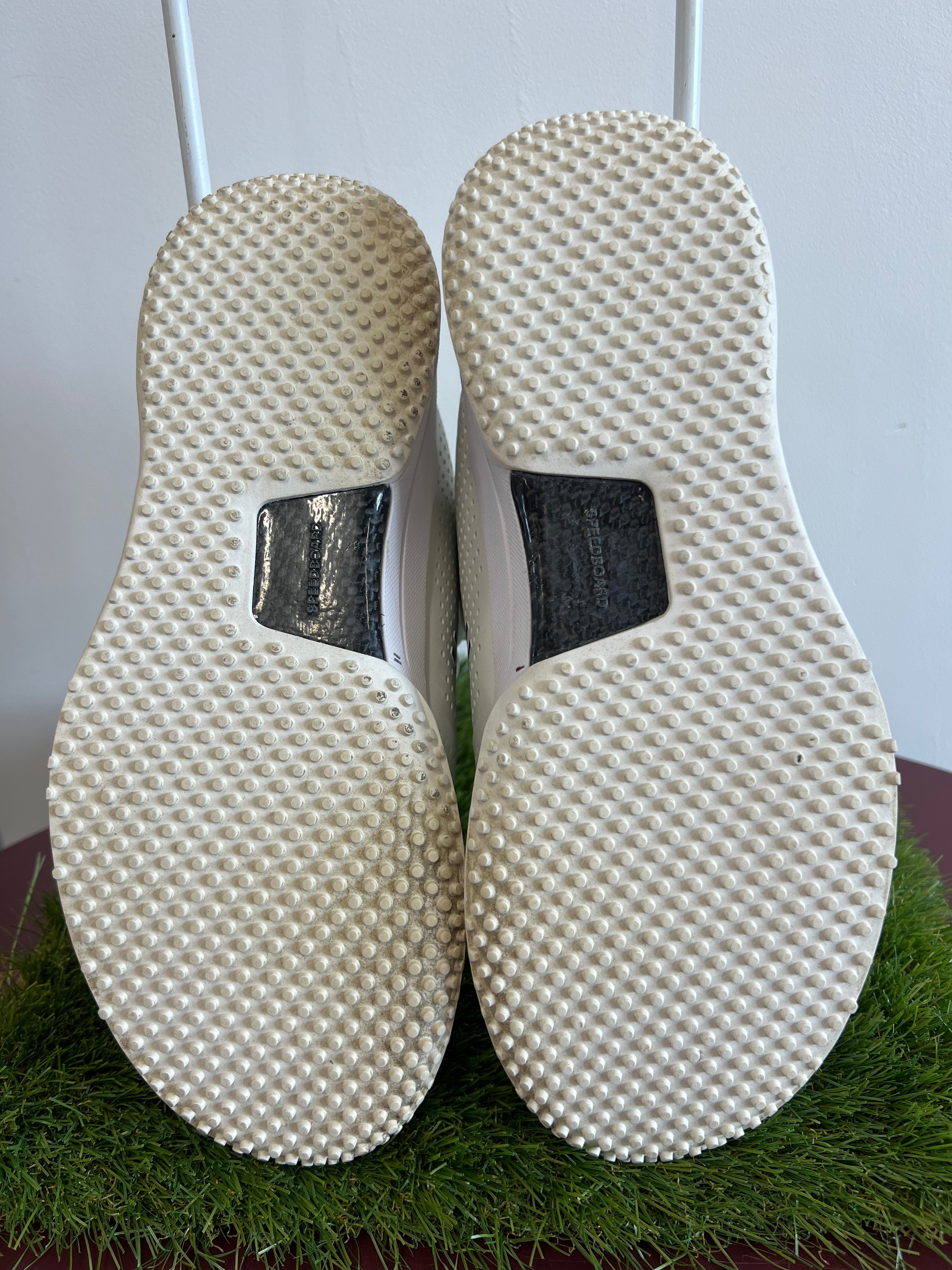 Underside view showing textured soles with black Speedboard insert on white trainers