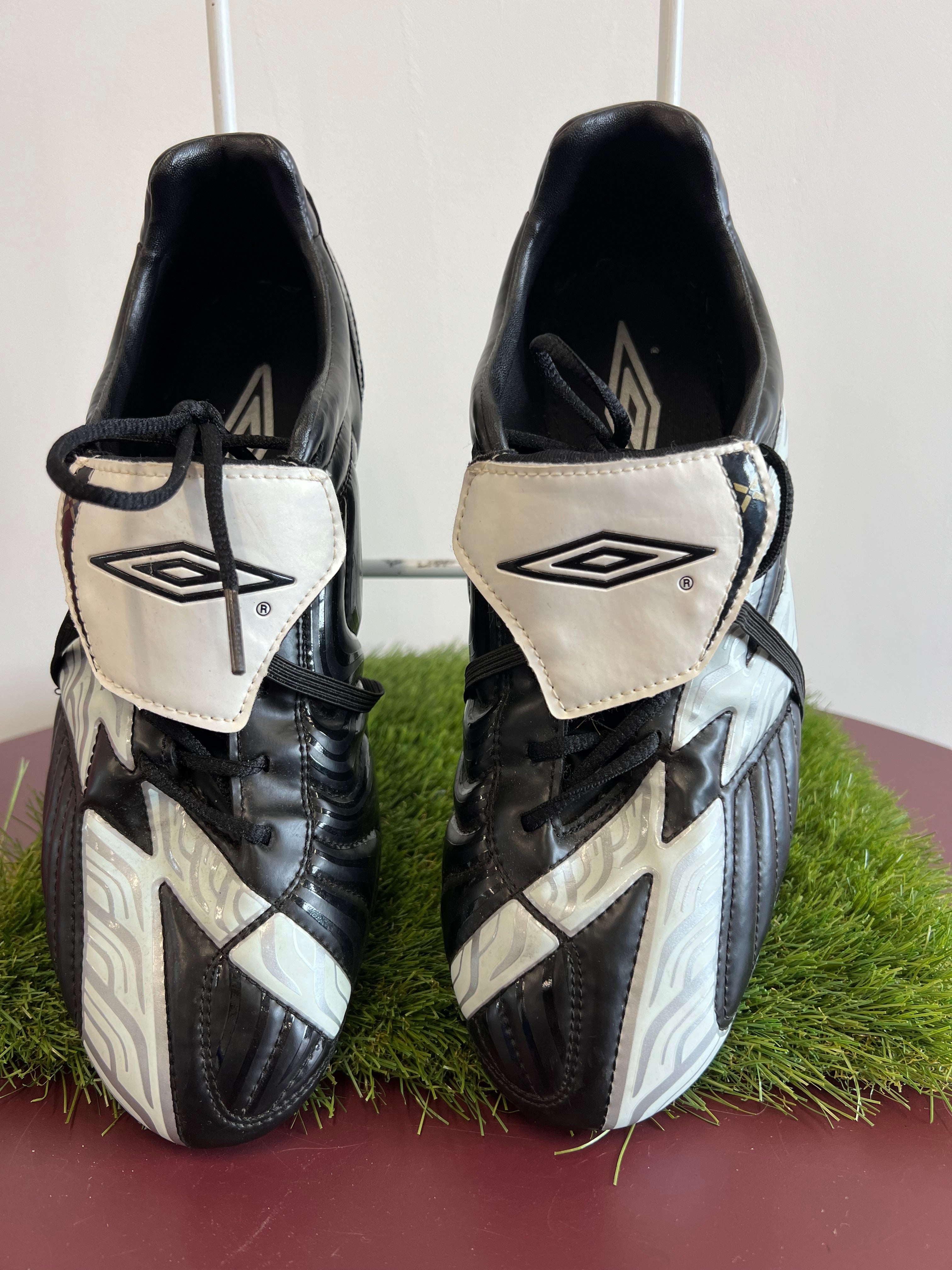 Pair of black and white Umbro football boots with padded upper and fold-over tongue showing Umbro logo