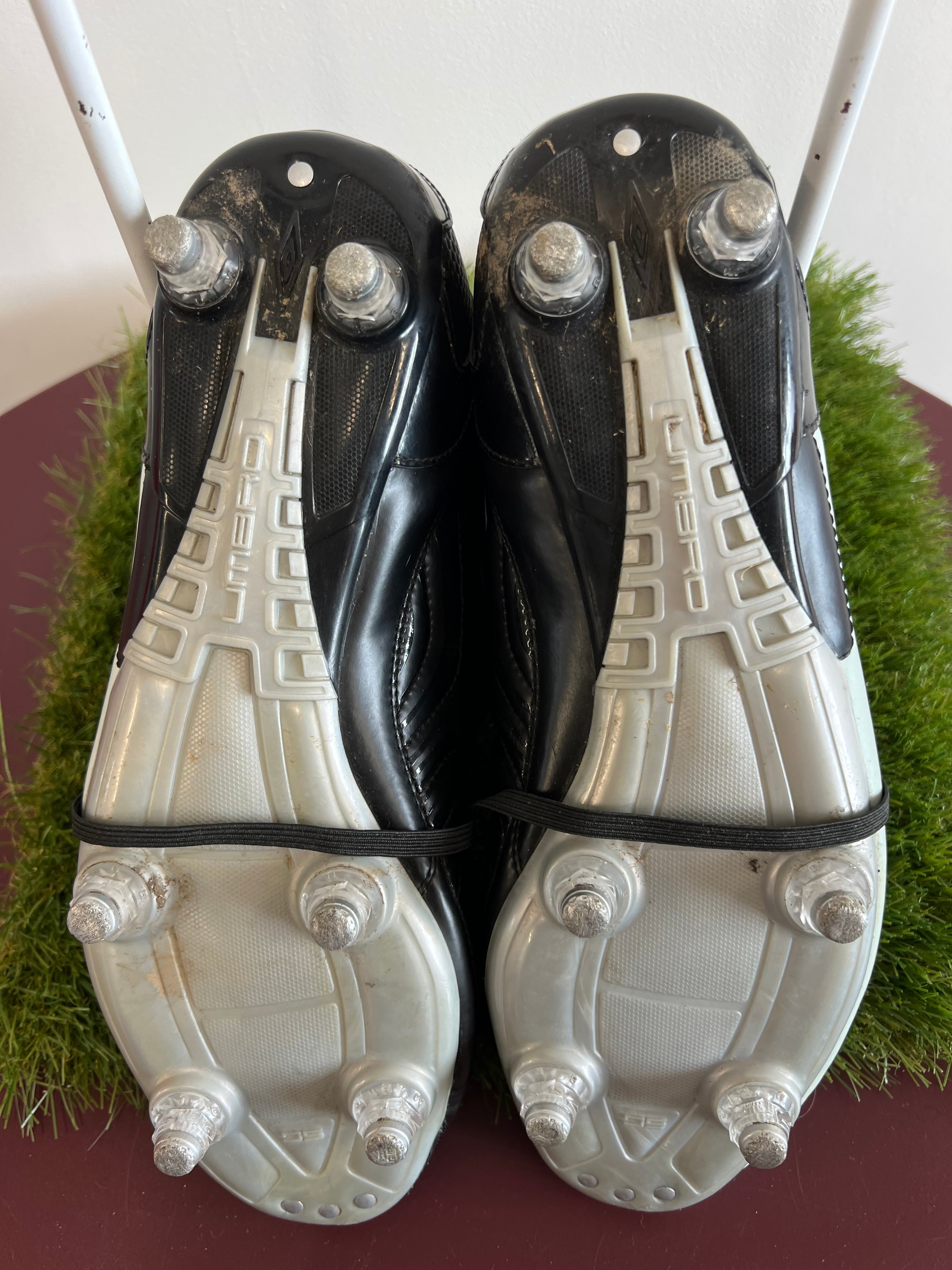 Close-up of the underside of Umbro football boots showing studded cleats designed for firm ground