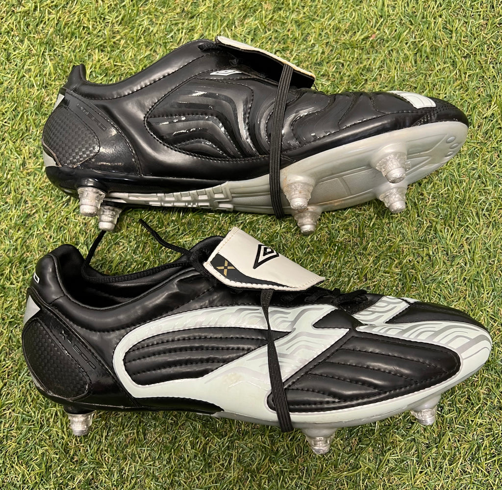 Side view of Umbro football boots highlighting black and white panel design with studs visible on the sole