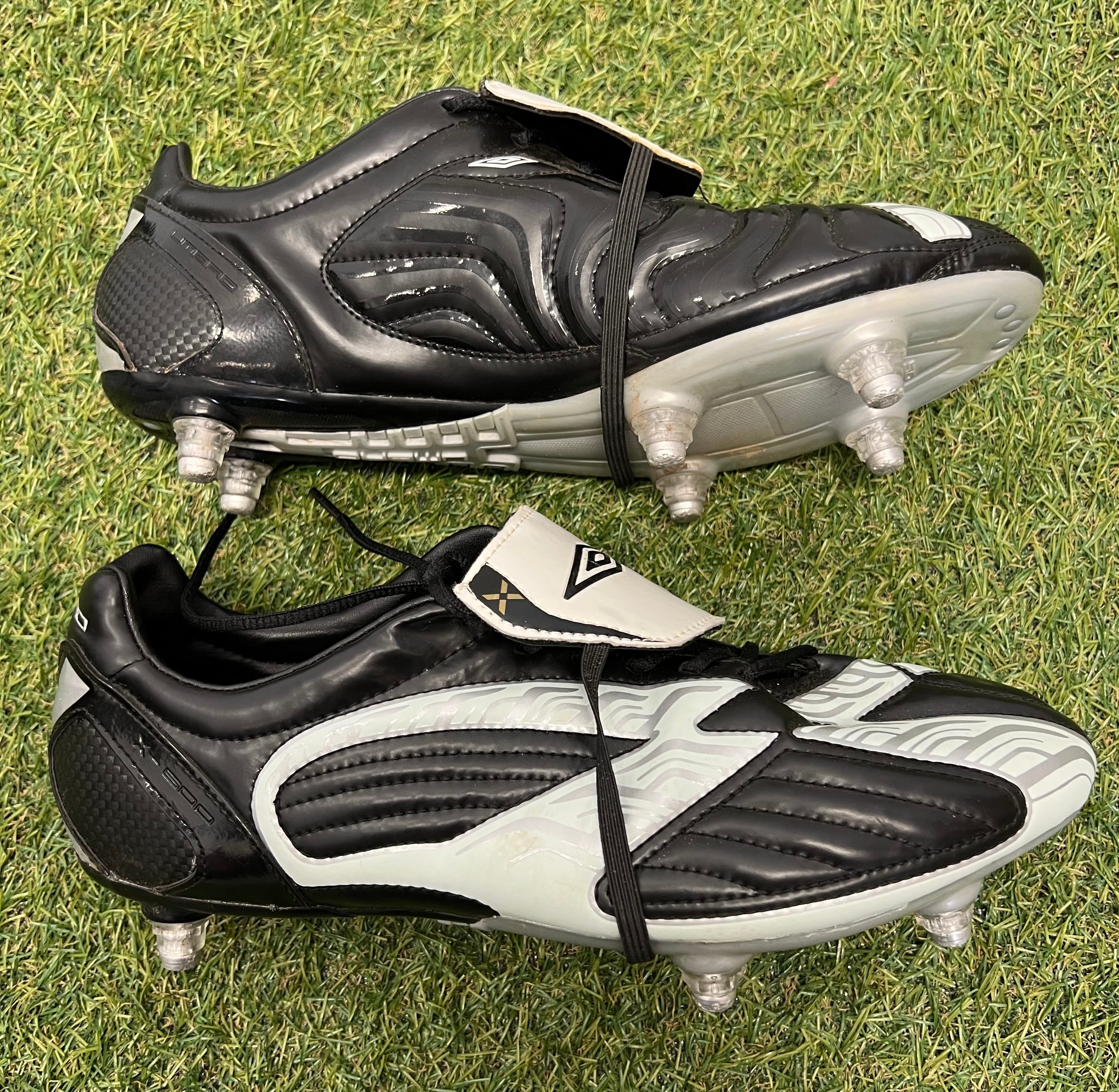 Side view of Umbro football boots highlighting black and white panel design with studs visible on the sole