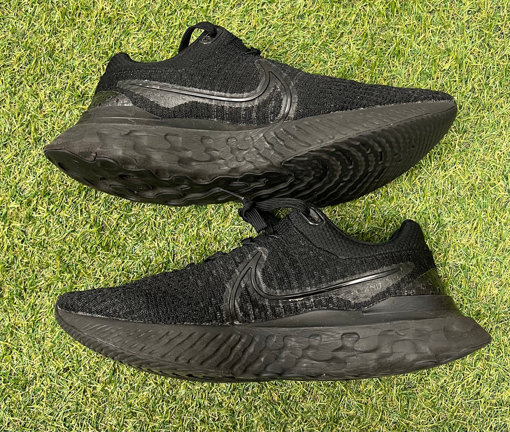 Side view of one Nike React trainer with textured black sole and knit upper on grass