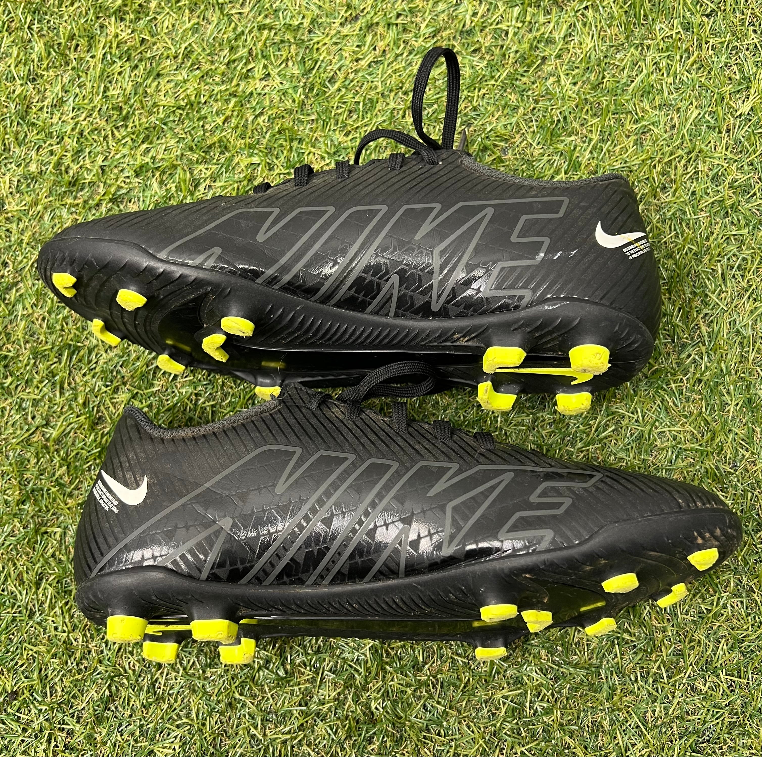 Side view of right black Nike Mercurial football boot showing large Nike print and yellow studs