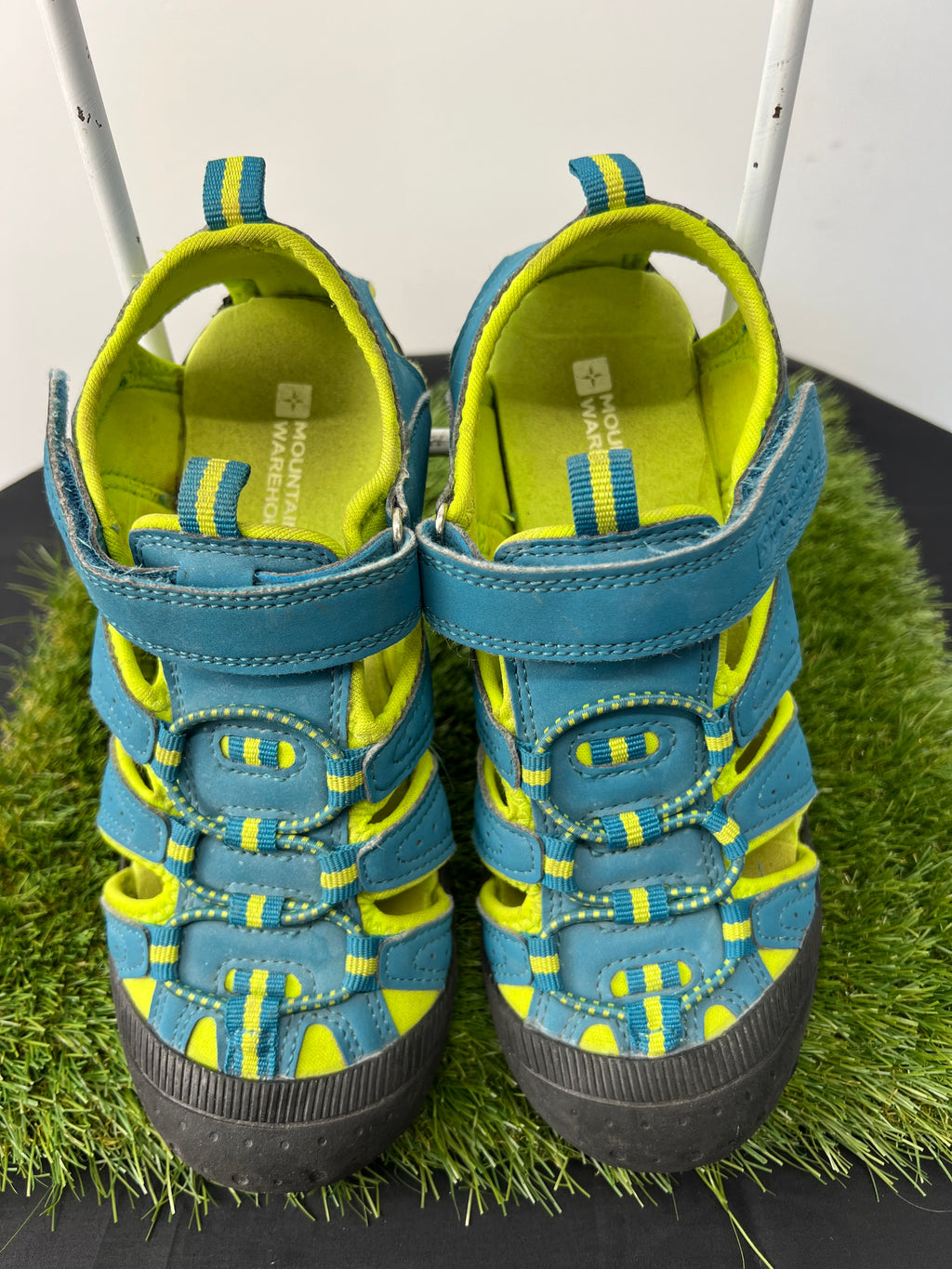 Pair of blue and yellow children's water sandals with hook-and-loop straps on grass