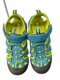 Pair of blue and yellow children's water sandals with hook-and-loop straps on grass